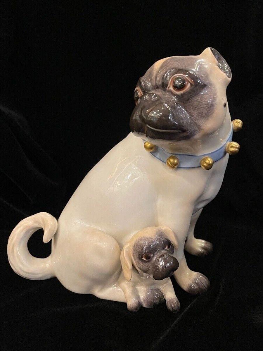 Meissen pug with a little puppy. Designed by J.J. Kaendler. This version ist almost 7,5 inches high. That little bells at the blue ribbon are rarer than another version with just the simple dog collar.

Markes 2nd choice. Size: 18 cm high.