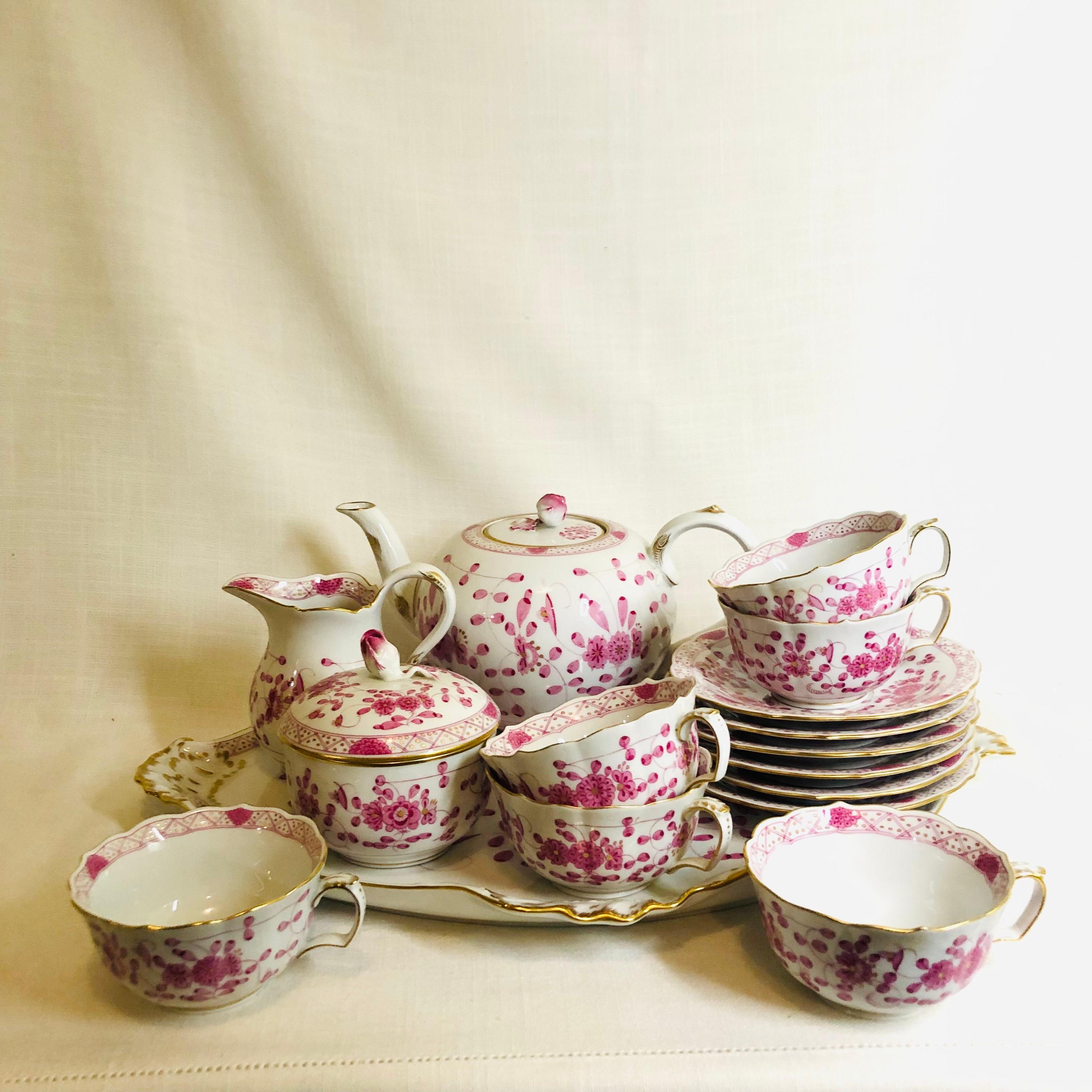 This is a beautiful Meissen purple Indian tea set comprising of a teapot, sugar and creamer, six tea cups and saucers and a serving tray. The teapot and the covered sugar are decorated with raised roses on their tops. All the pieces of the tea set