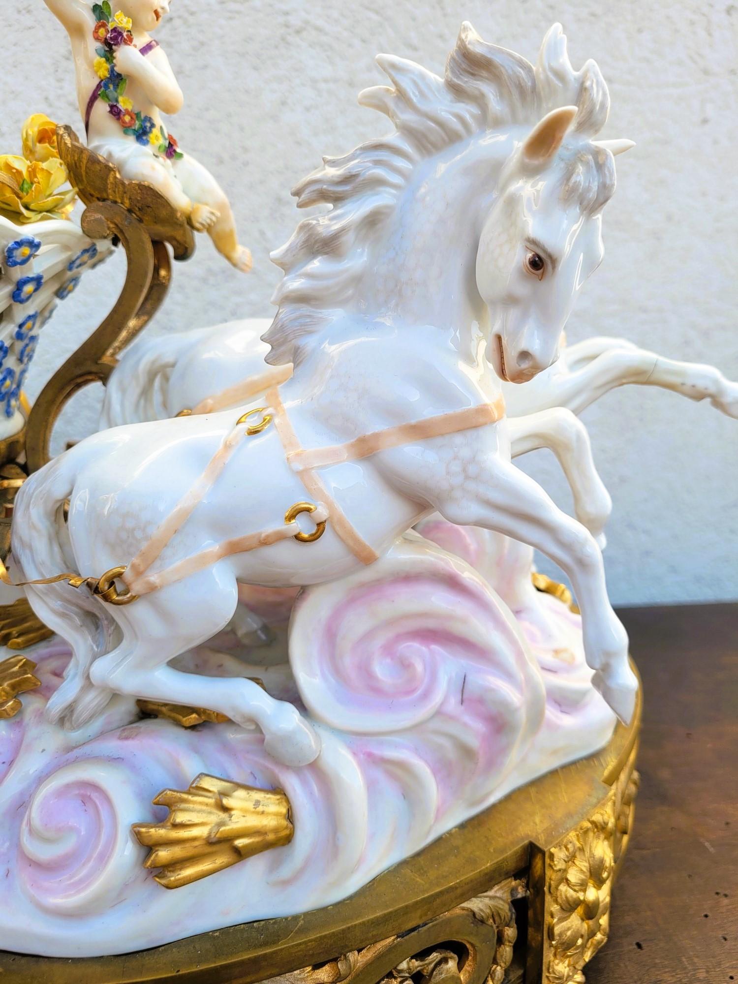Grande soggetto in porcellana bianca e colorata, di un putto che guida un carro pieno di fiori di porcellana, trainato da 4 cavalli

Per una maggiore raffinatezza, questo set è posizionato su una base originale in bronzo dorato, la porcellana è come
