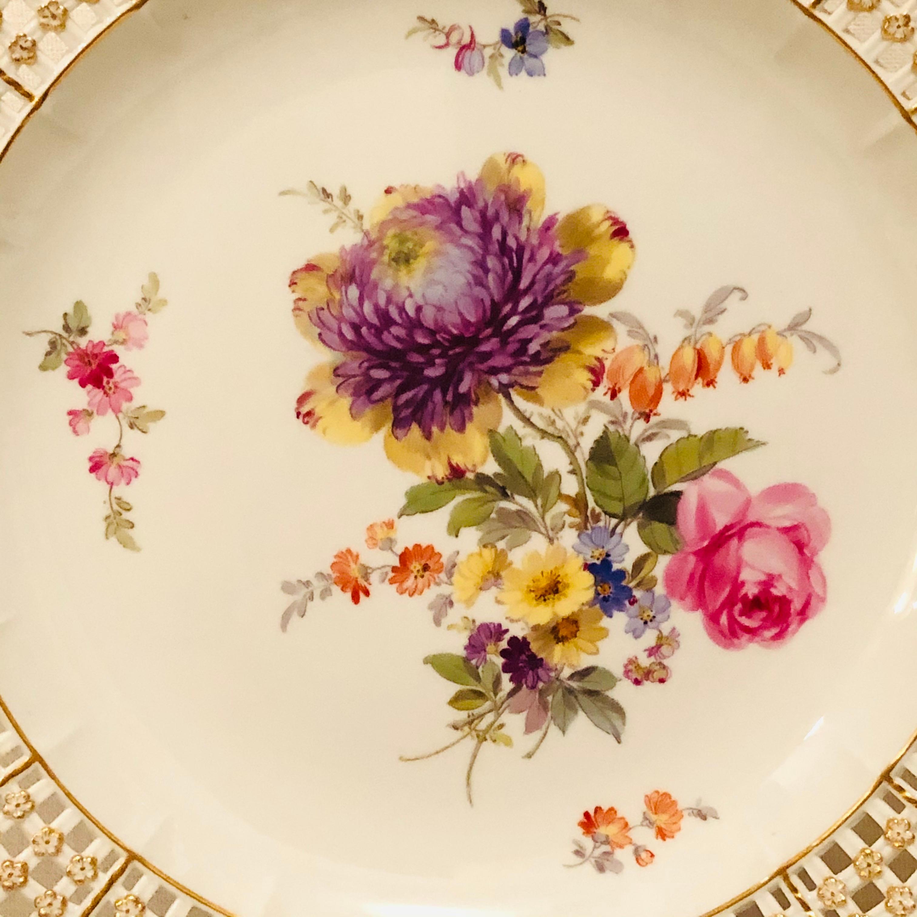 This is an exquisite Meissen cabinet plate painted with a large beautiful flower bouquet. The Meissen plate has a very intricate reticulated or open work border profusely decorated with raised gold and blue forget me nots. This Meissen plate is from