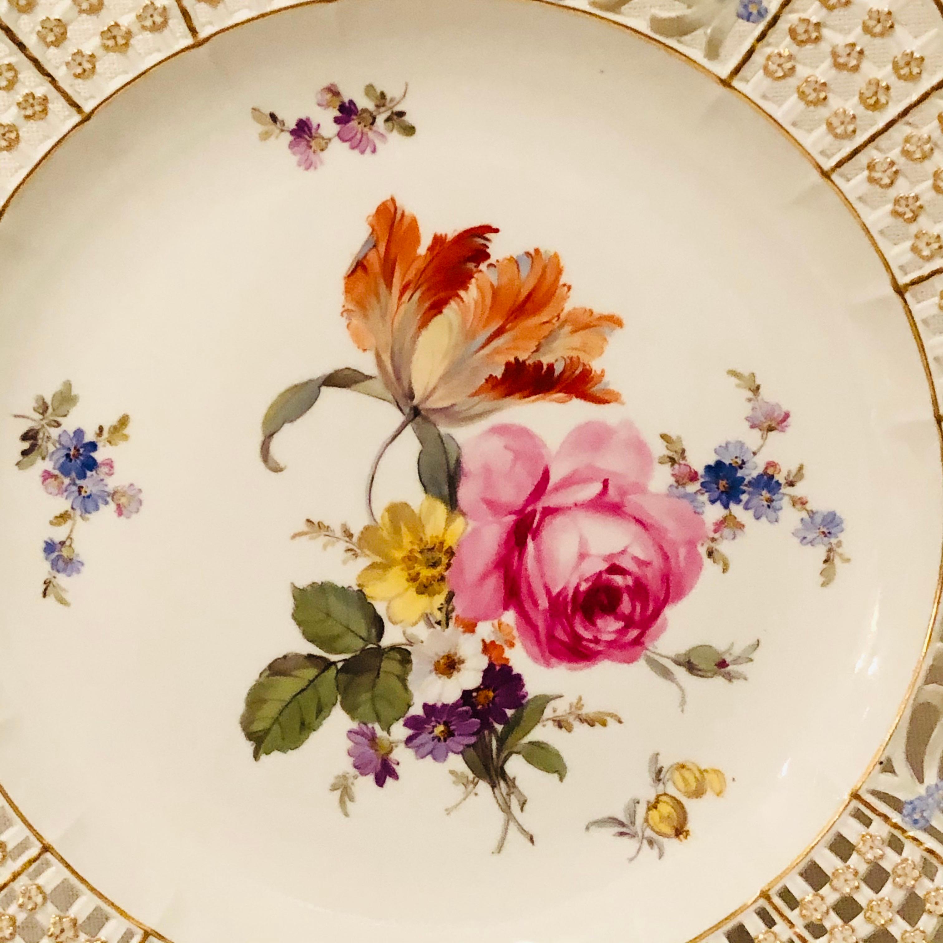 This is an exquisite Meissen cabinet plate painted with a large beautiful flower bouquet with a large tulip and other flowers. The Meissen plate has a very intricate reticulated or open work border profusely decorated with raised gold and blue