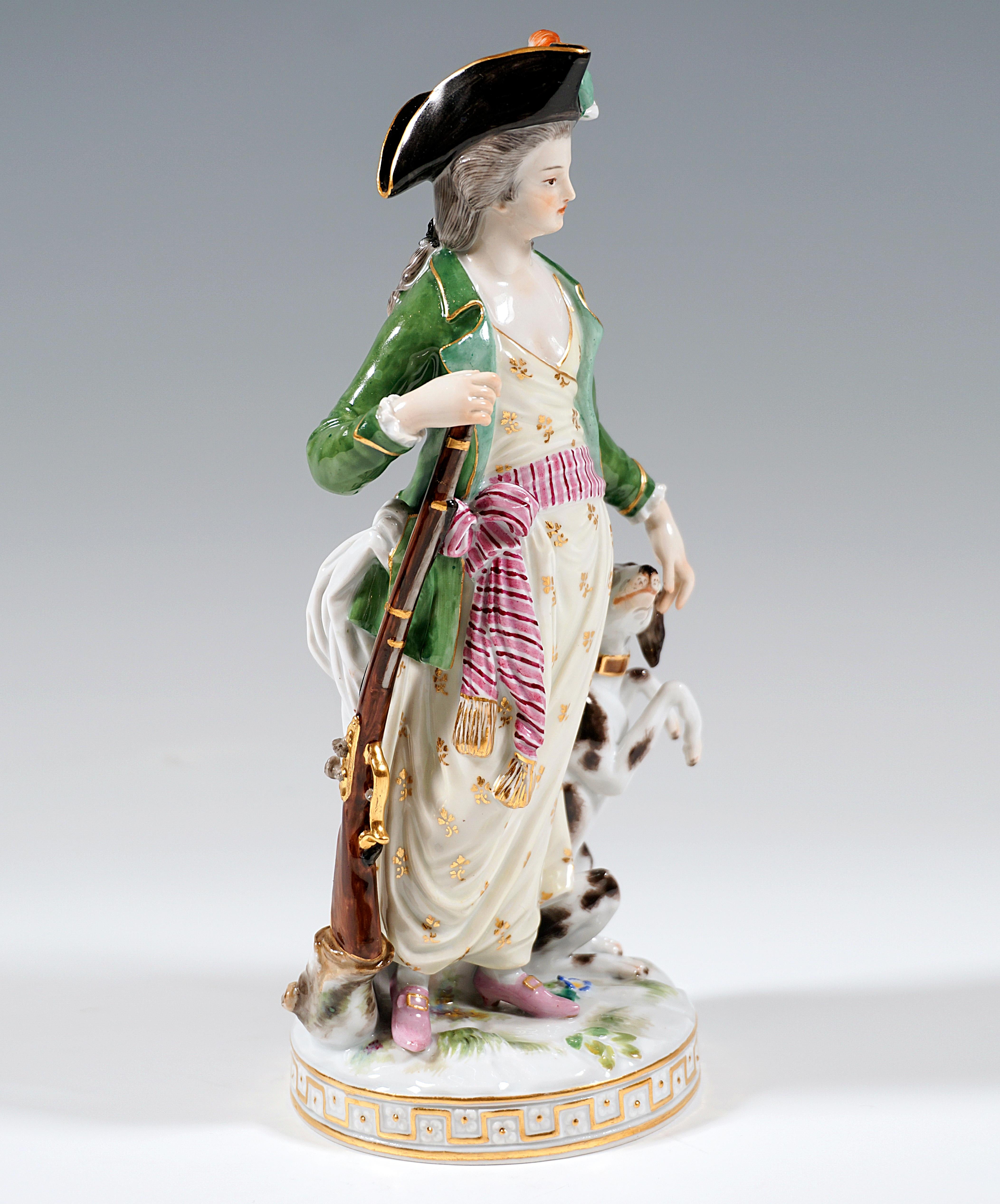 Elaborate porcelain figure of the 19th century:
Young lady with rococo wig dressed as a huntress: black trident hat with colorful feather decoration, softly falling dress embracing the body with pink striped scarf as a belly bandage, on the feet