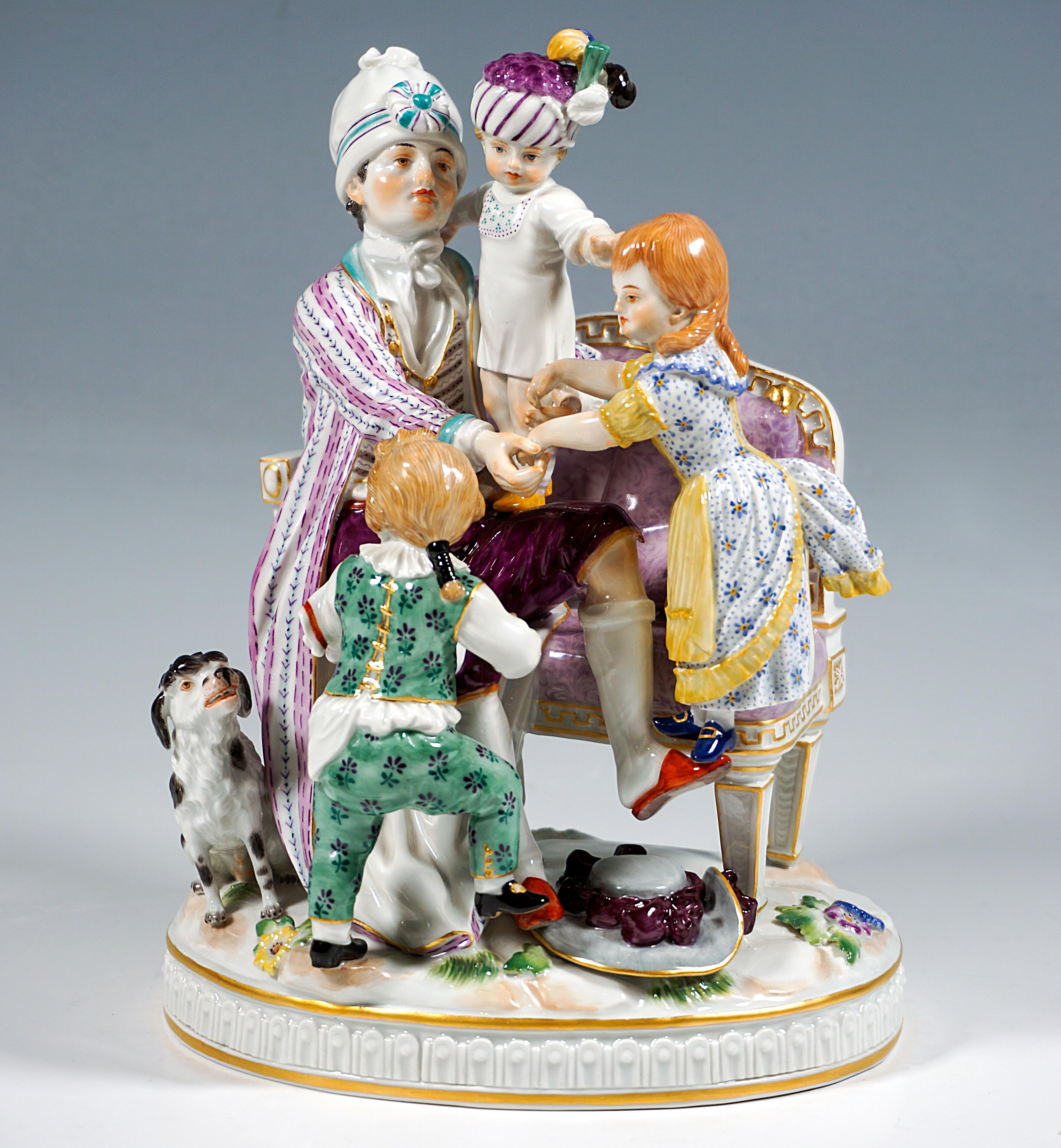 Excellent Meissen porcelain genre group:
The father in domestic garb (housecoat over elaborate house clothes, slippers, high cap) sitting on a cushioned bench and busy supervising his three children: A small boy in a white shirt and turban adorned