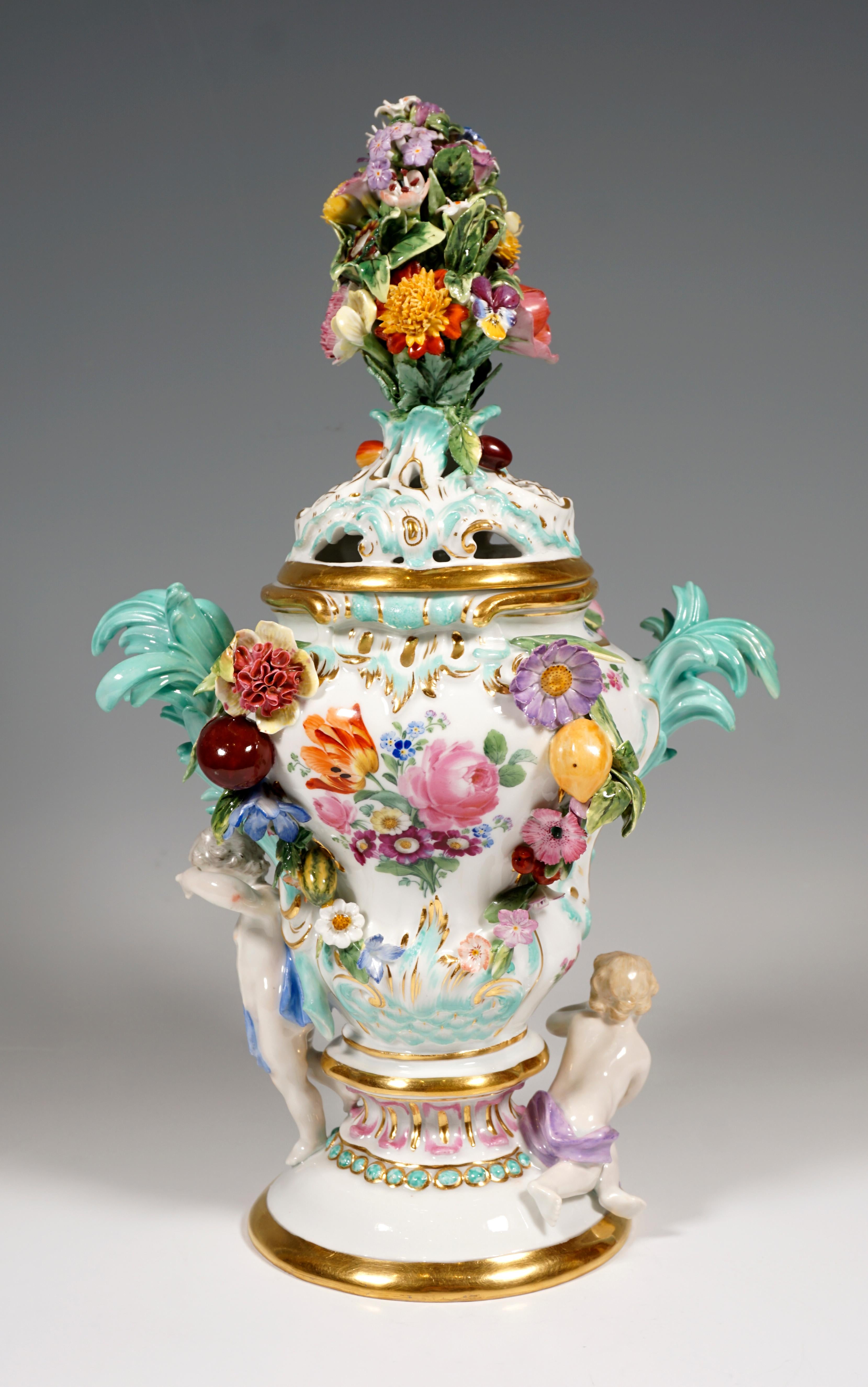 Balusterförmige Vase auf gestuftem, rundem Sockel mit durchbrochen gearbeitetem Deckel, reich verziert mit plastisch und farbig dekorierten Blüten, Blättern, Früchten und Rocaillen sowie zwei seitlichen Amoretten. Vorder- und Rückseite mit gemalter