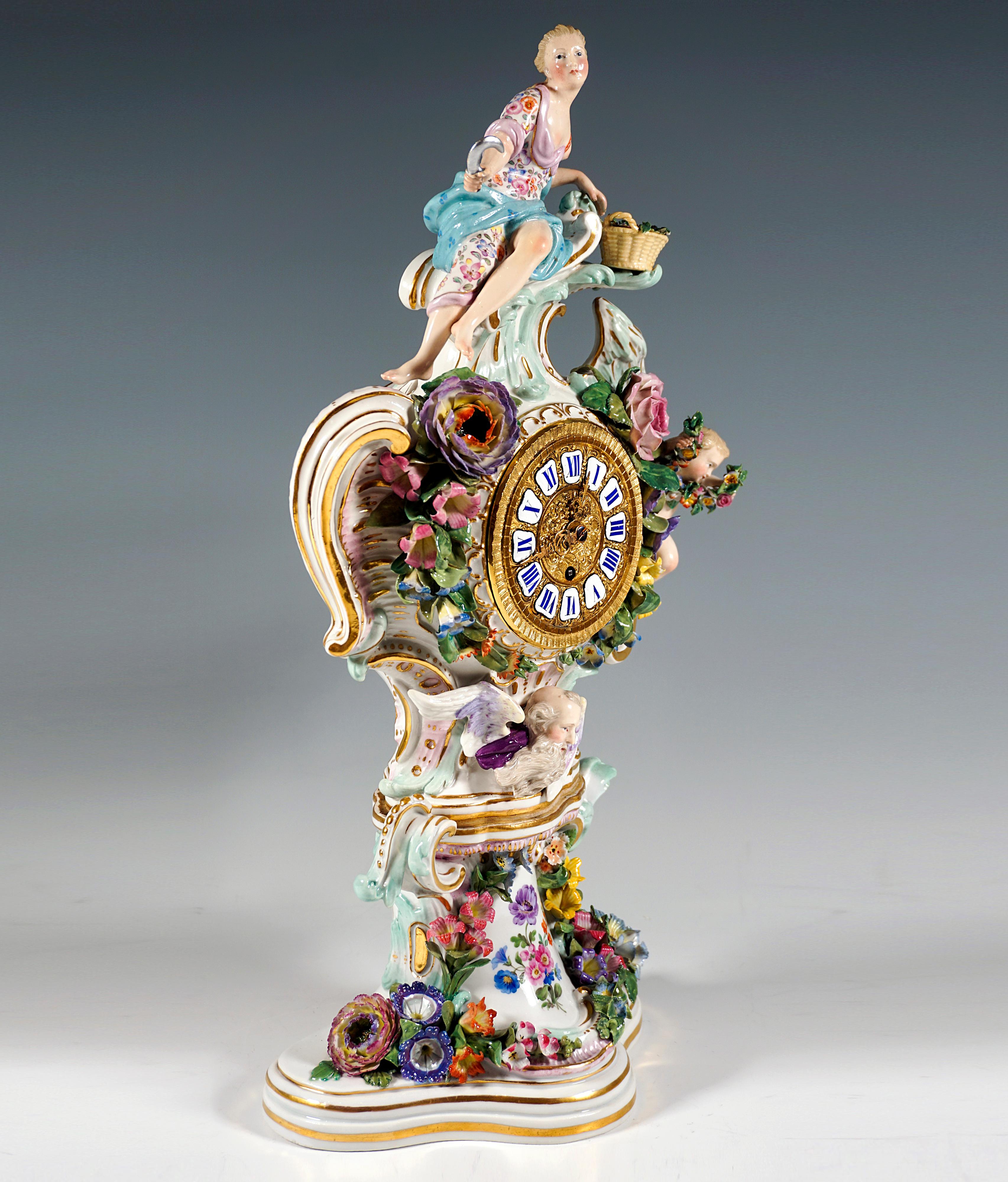 Clock case rising on a column with a three-passage base, richly decorated with rocailles and delicate, plastically formed flowers and leaves 
surrounding the dial, crowned by a flora with a sickle and flower basket leaning sideways on a beveled