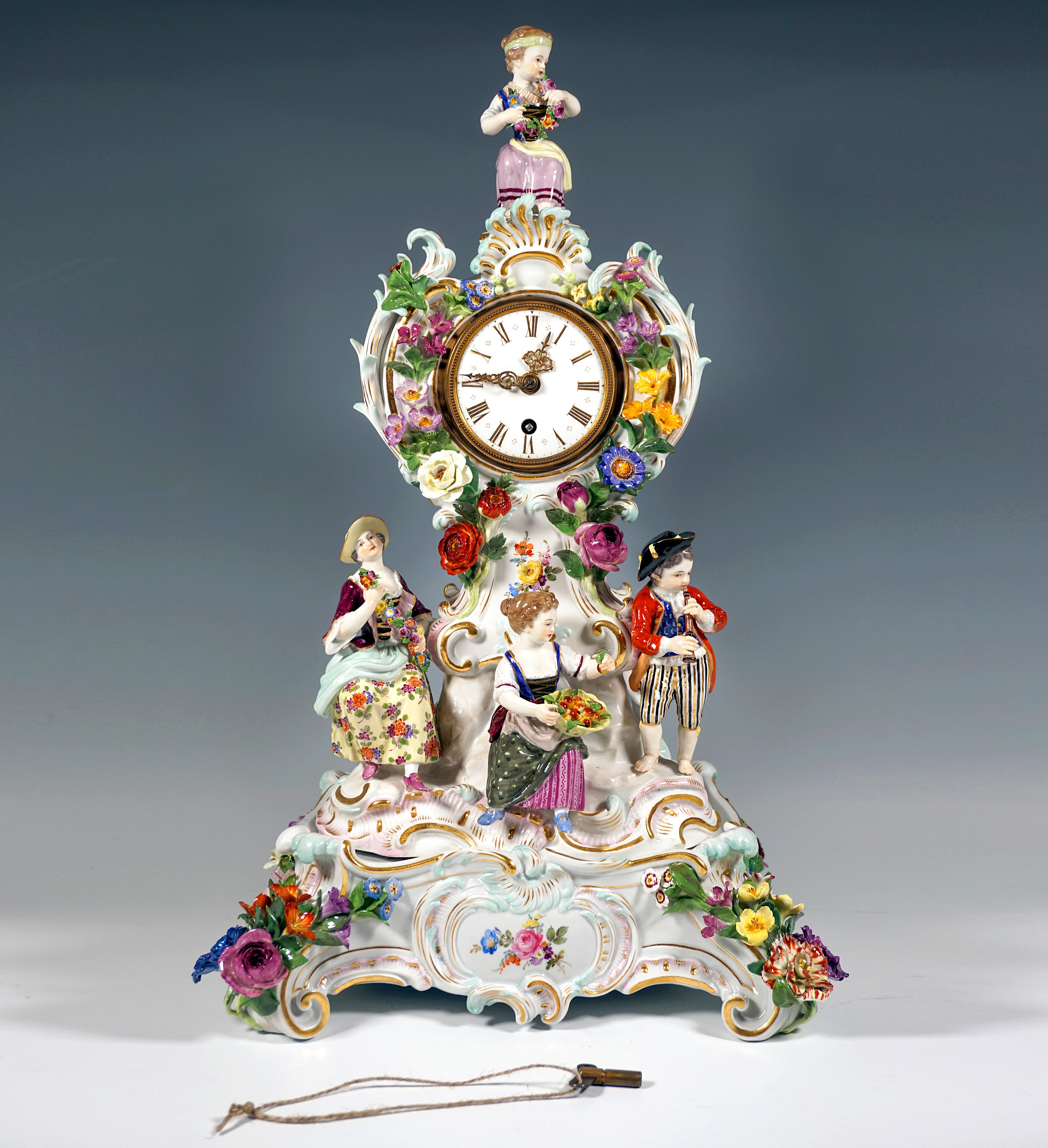 The clock and the pedestal were designed by Leuteritz using old forms in the Rococo style:
The clock case rises on a rock base with gold heightened rocailles, richly decorated with delicate, sculpted flowers, leaves and rocailles that play around