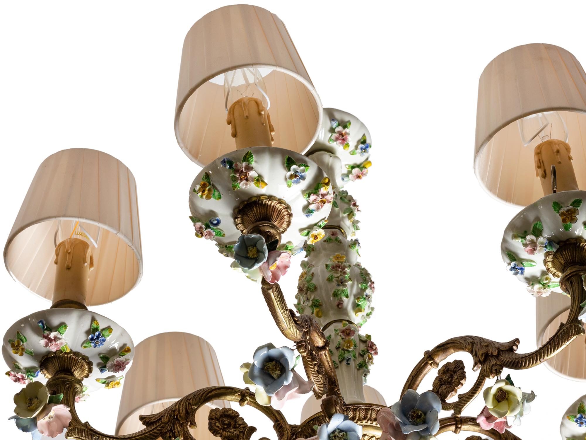 Questo elegante lampadario dell'inizio del XX secolo combina la porcellana dipinta a mano in stile Meissen con una cornice in bronzo dorato. 
Presenta sei bracci curvi, ognuno dei quali sostiene prese a candela e bobèches floreali in porcellana con