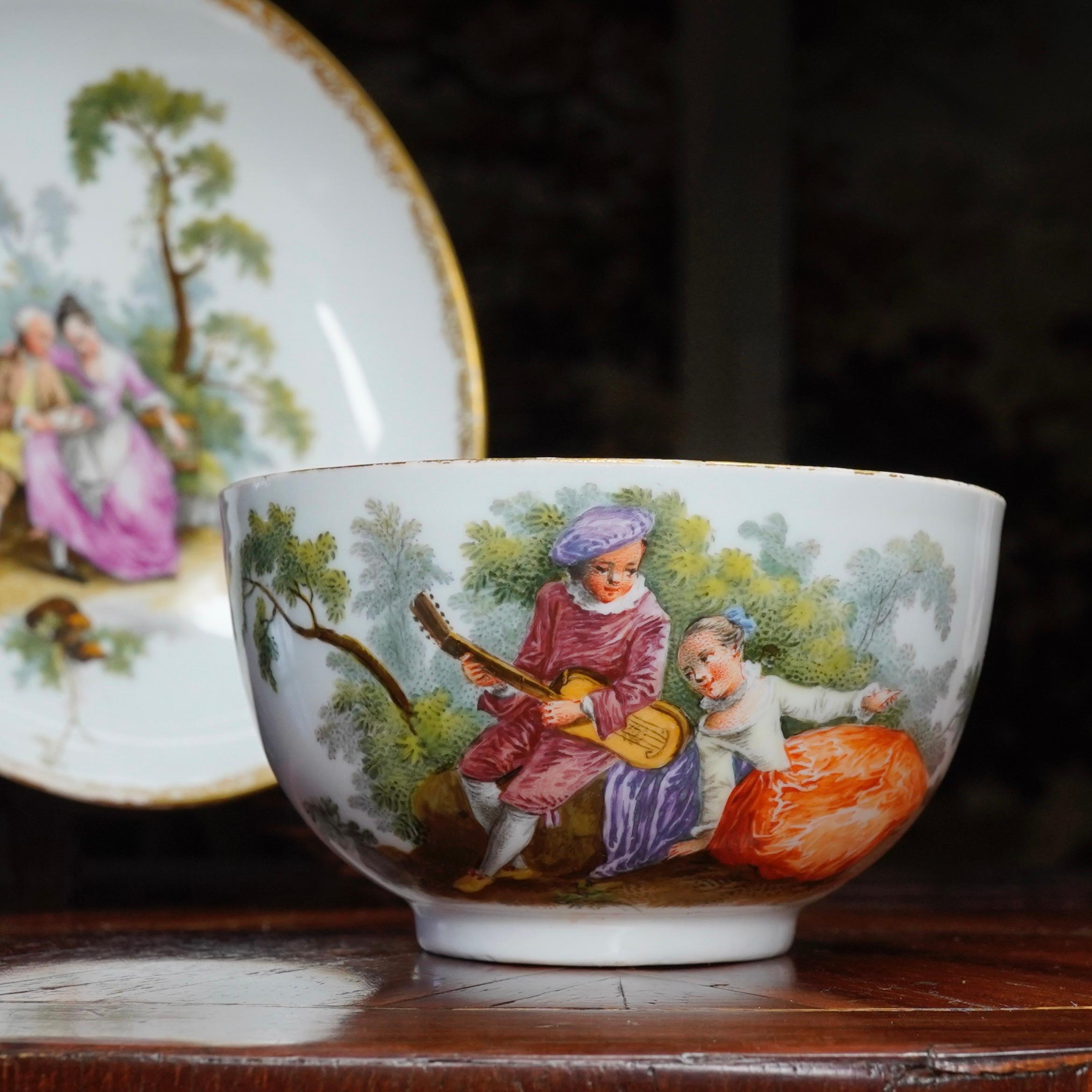 Meissen tea bowl and saucer, superbly painted with large scale Watteauesque scenes of couples in garden, within a fine gold tracery border. 

Blue crossed swords and dot mark, 

circa 1770.