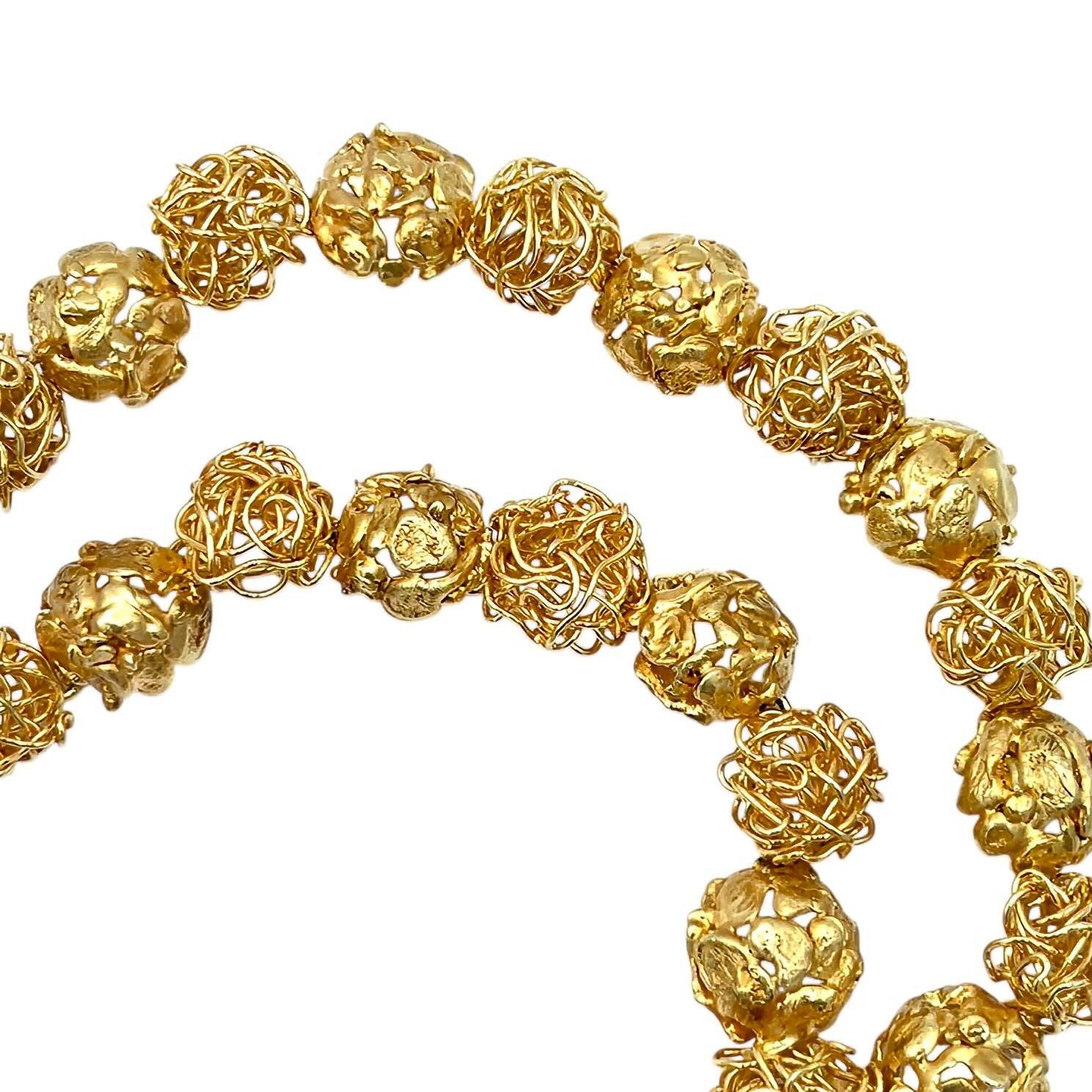 An 18 karat yellow gold necklace, Meister.  Designed as a length of round convex links alternating between wirework and abstract foliate motifs suspending a pendant of convex wirework surrounded by additional abstract foliate motifs.  Length