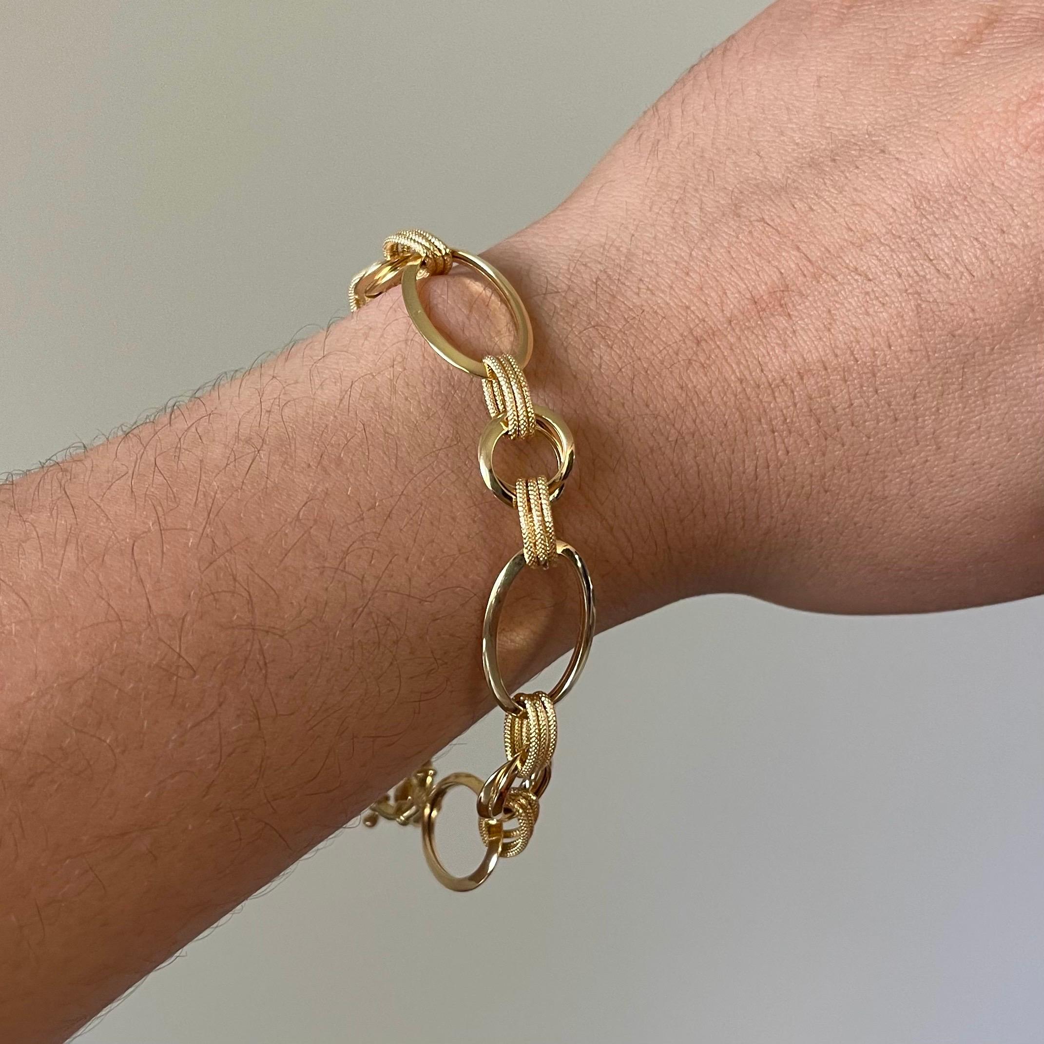 This unique 18k gold bracelet showcases a striking combination of high-polish oval links and finely textured rings, creating a dynamic silhouette that’s both bold and refined. Its artful construction adds graceful movement and a touch of