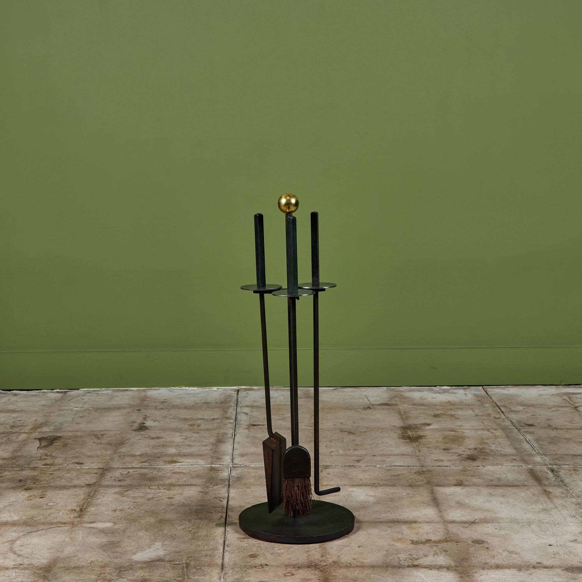 Fireplace tool set designed by Mel Bogart for Felmore, USA, c.1950s. The set features three wrought iron fireplace tools with a stainless steel disk detail near the handle, all set on a matching base topped off with a brass ball. A staple in modern