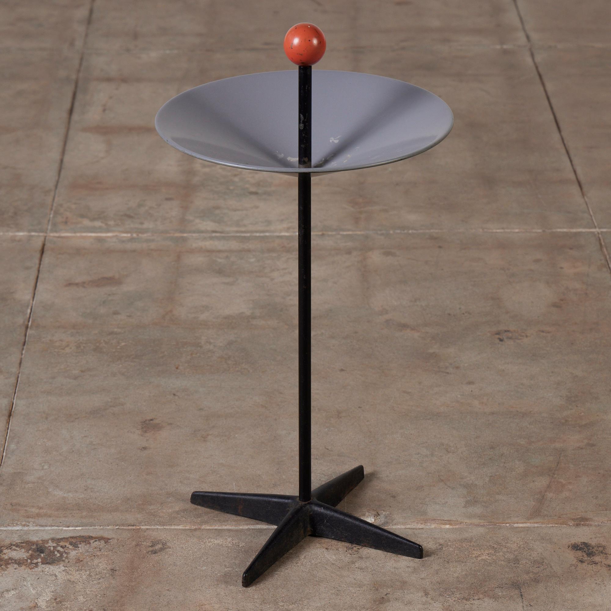 A modernist freestanding ashtray/catch-all designed by Mel Bogart for Felmore, USA, c.1950s. It features an enameled metal dish that wraps around an iron stem, atop a four-star base, and is topped off with a bright orange ball, a staple in modern