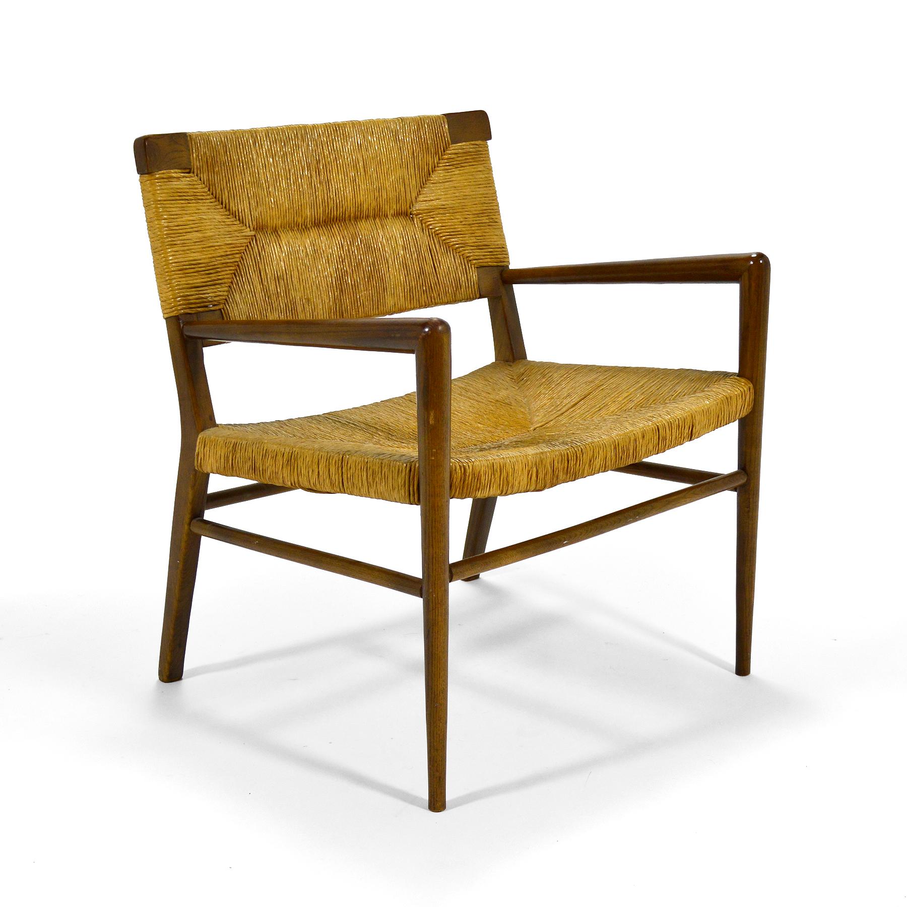 The subtle, almost austere design of Mel Smilow's lounge chair positions it somewhere between a Scandinavian and French aesthetic. The walnut frame supports a seat and back of woven rush. The rakish, angular design points to its midcentury pedigree.