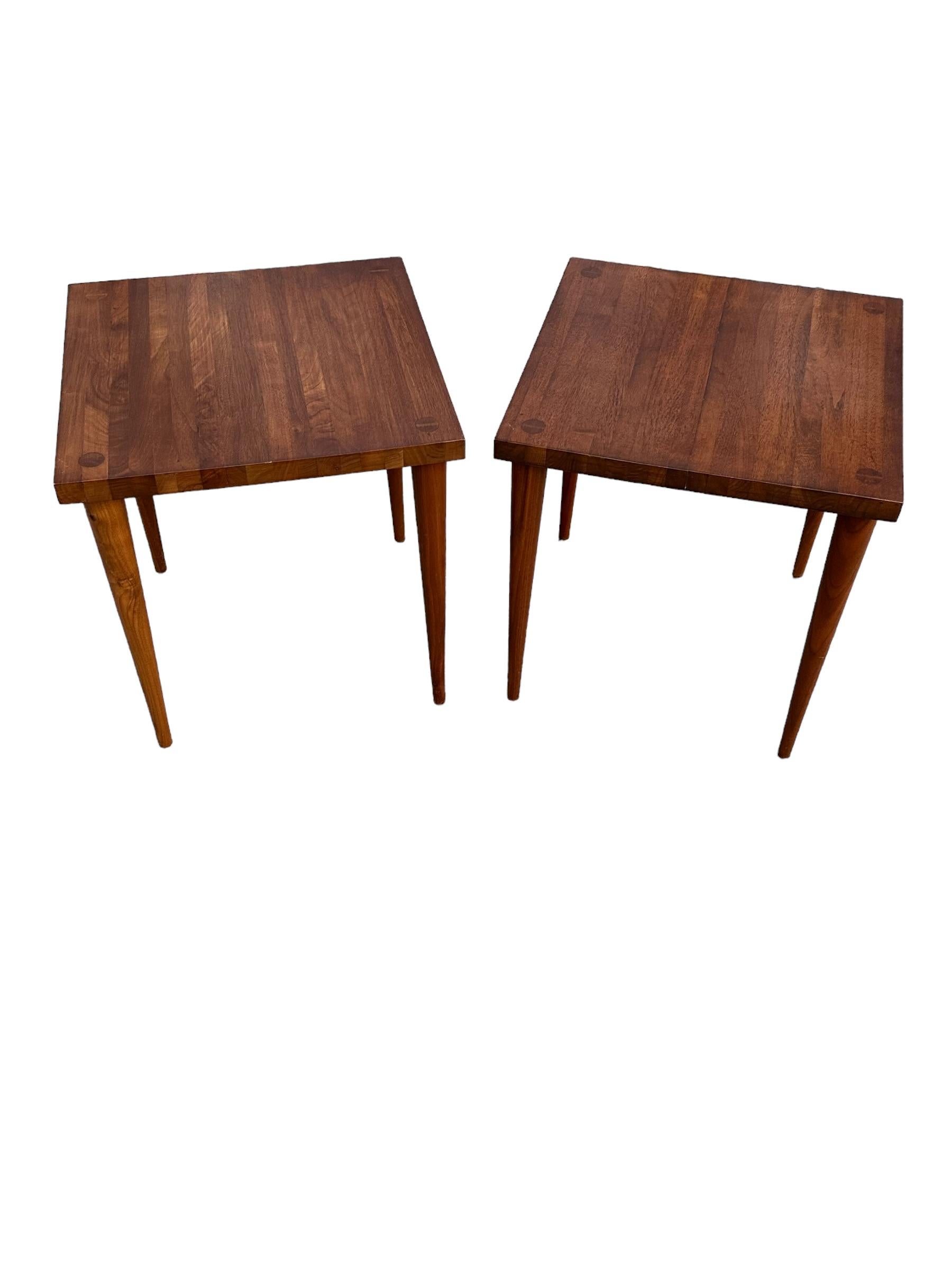 Classic modernist simplicity and elegance in this pair of solid wooden side tables. Designed by Mel Smilow and executed in American Walnut. Butcher blocks style tops without chunky silhouette. Tapered legs with visible joinery are honest and