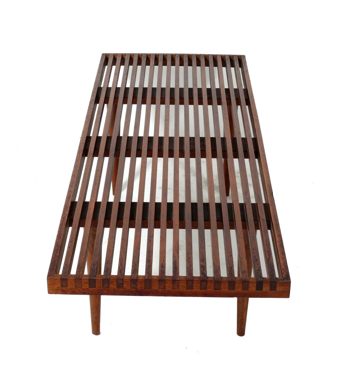 Midcentury walnut slat bench or coffee table, designed by Mel Smilow, American, circa 1950s. It has Smilow's signature joinery at the corners of the bench. It is a versatile size and can be used as a bench or coffee table. It has been cleaned and