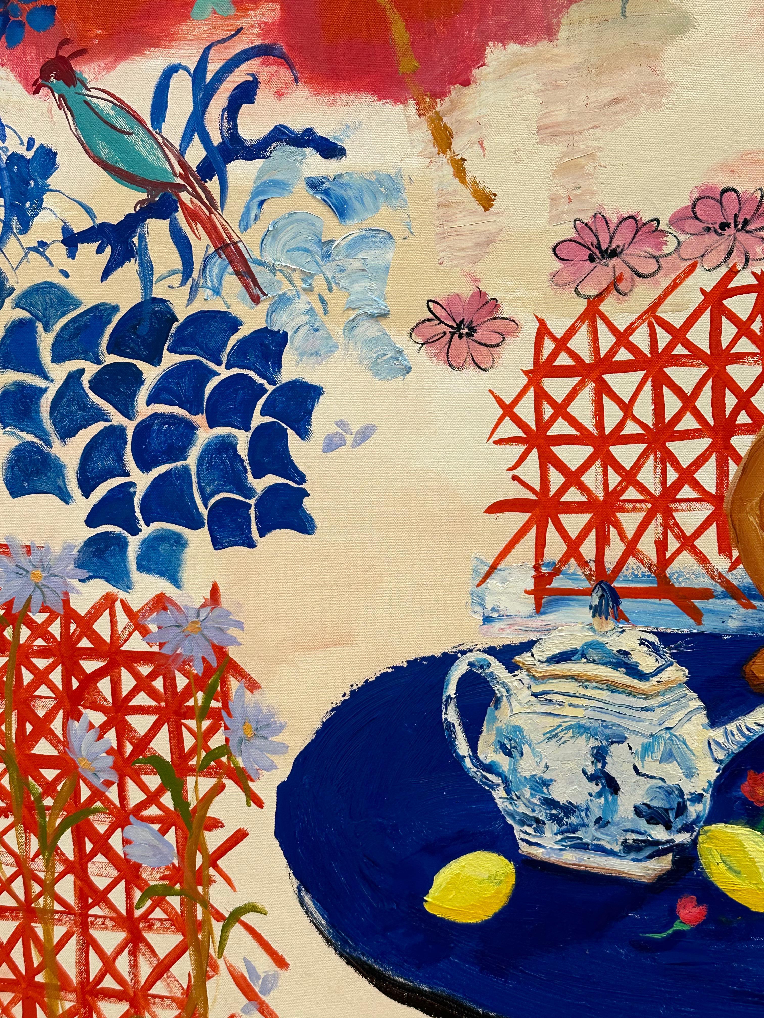 Ein lebhaftes und farbenfrohes Esszimmerinterieur mit einem Blumenarrangement in einer bemalten Vase neben einer blau-weißen China-Teekanne, einer nackten Figur und verschiedenen Früchten, gelben Zitronen, Birnen und grünen Limetten auf einem blauen