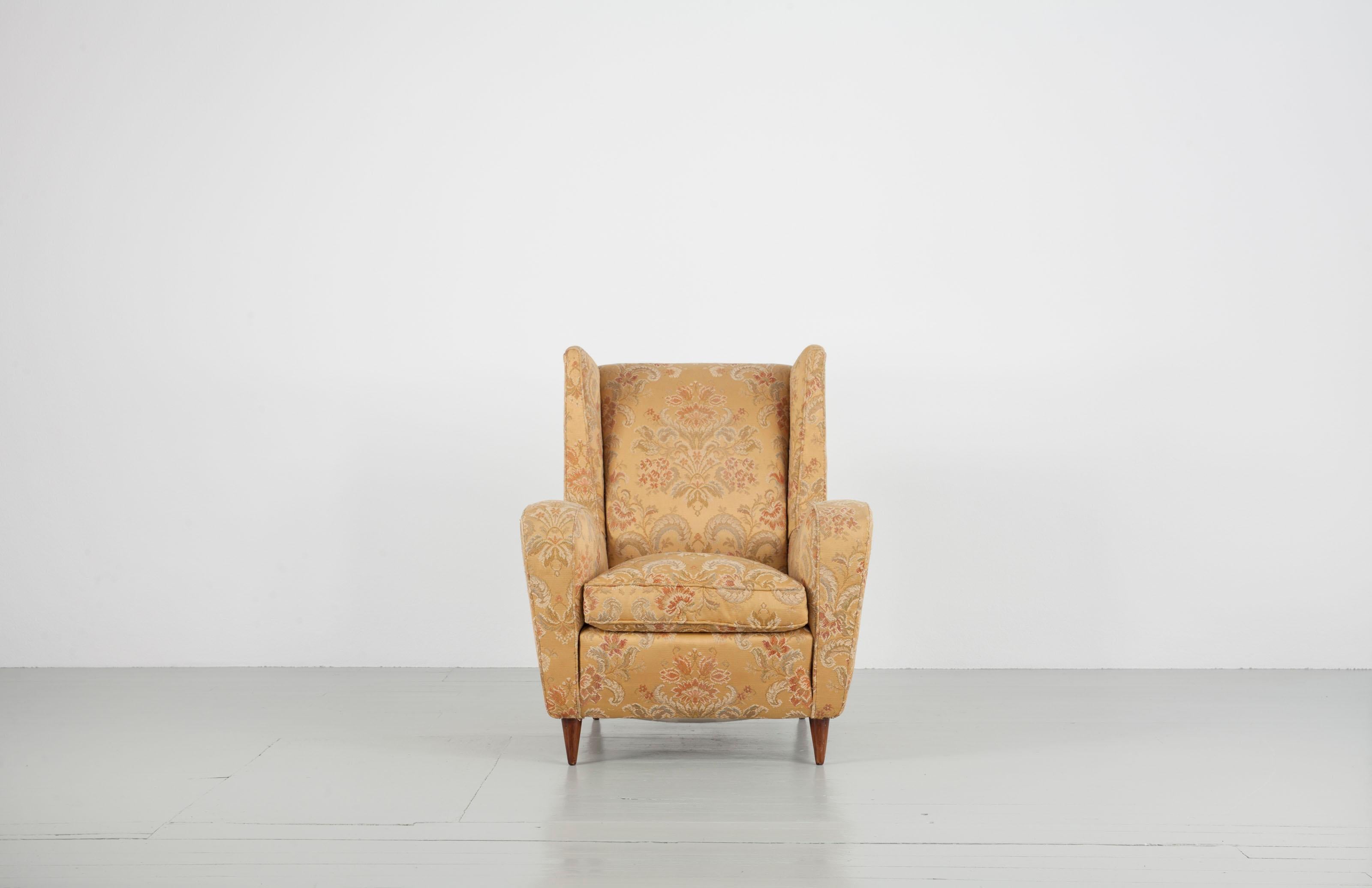 Armchair designed by Melchiorre Bega. These elegantly proportioned wingback chair features tapered walnut legs and is upholstered in its original fabric in a golden color and with ornamentals.

    
