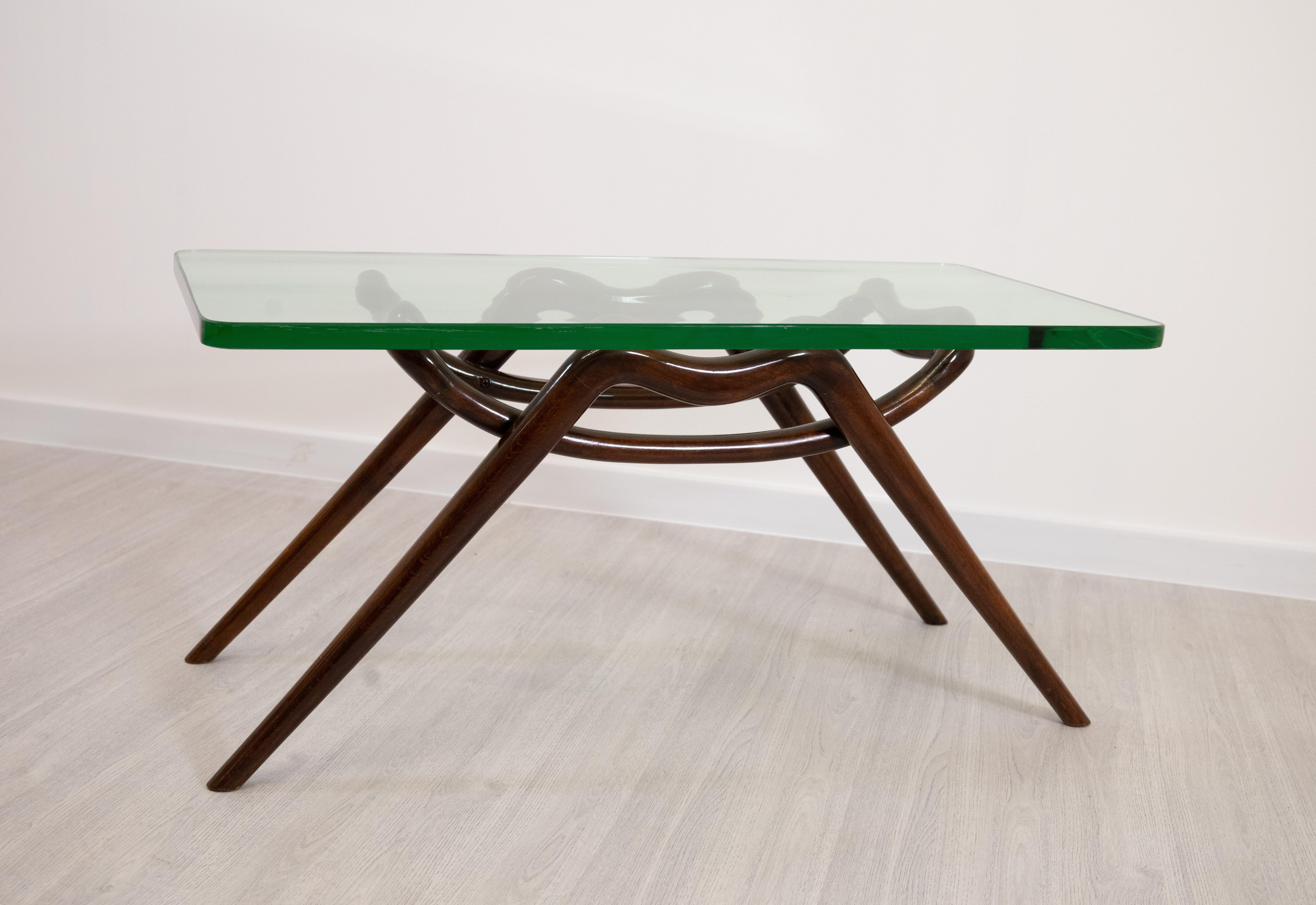 Elégante table basse attribuée à Melchiorre Bega, datant des années 1950, fabriquée en Italie. Ce meuble raffiné allie la chaleur du bois courbé à la légèreté d'un plateau en verre de 2 cm d'épaisseur, créant ainsi un équilibre parfait entre forme
