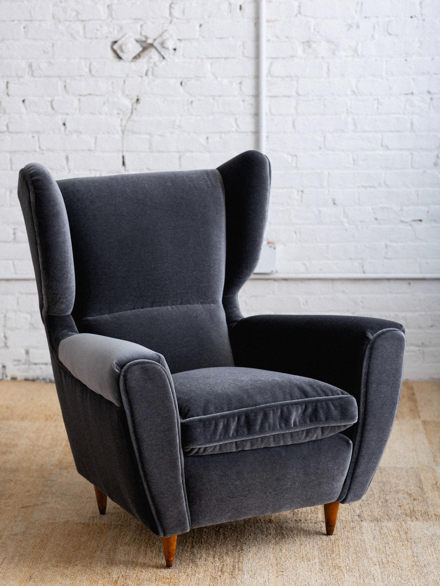 A mid century Italian armchair attributed to Melchiorre Bega. Wingback silhouette. Newly upholstered in a high pile plush grey mohair. Down seat cushion. Original wood feet. Sourced in Northern Italy. Pair available, sold individually.