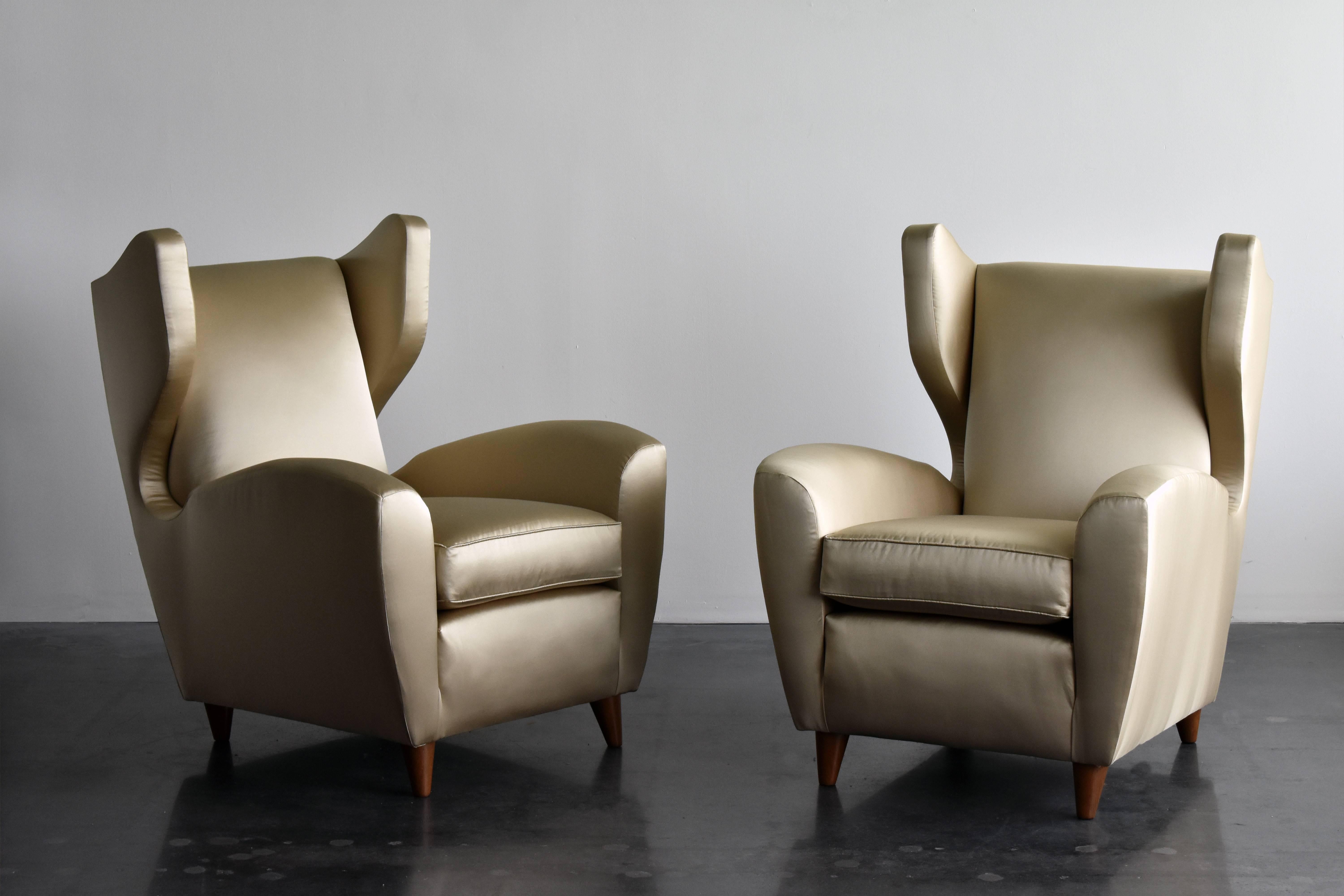 Ein Paar organische Lounge-/Wingback-/Hochlehner-Stühle, entworfen und hergestellt vom italienischen Architekten Melchiorre BEGA. Holzbeine, gepolstert mit brandneuem hellgoldenem/bronzefarbenem Metallic-Satin-Stoff. 

Melchiorre BEGA gilt als einer