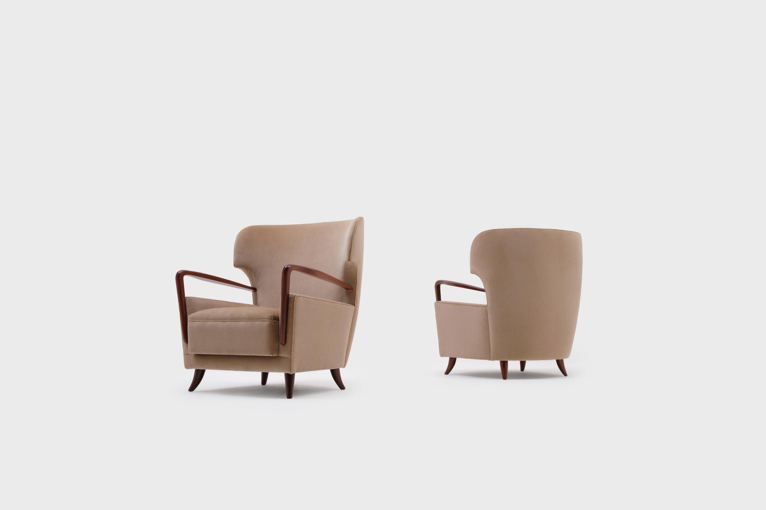 Rare set of wingback armchairs by Melchiorre Bega (1898-1976), Italy, 1950s. Stunning and exceptional design from the highest quality. The sharp wingback and organically carved armrests and feet out of solid mahogany are the signature of this