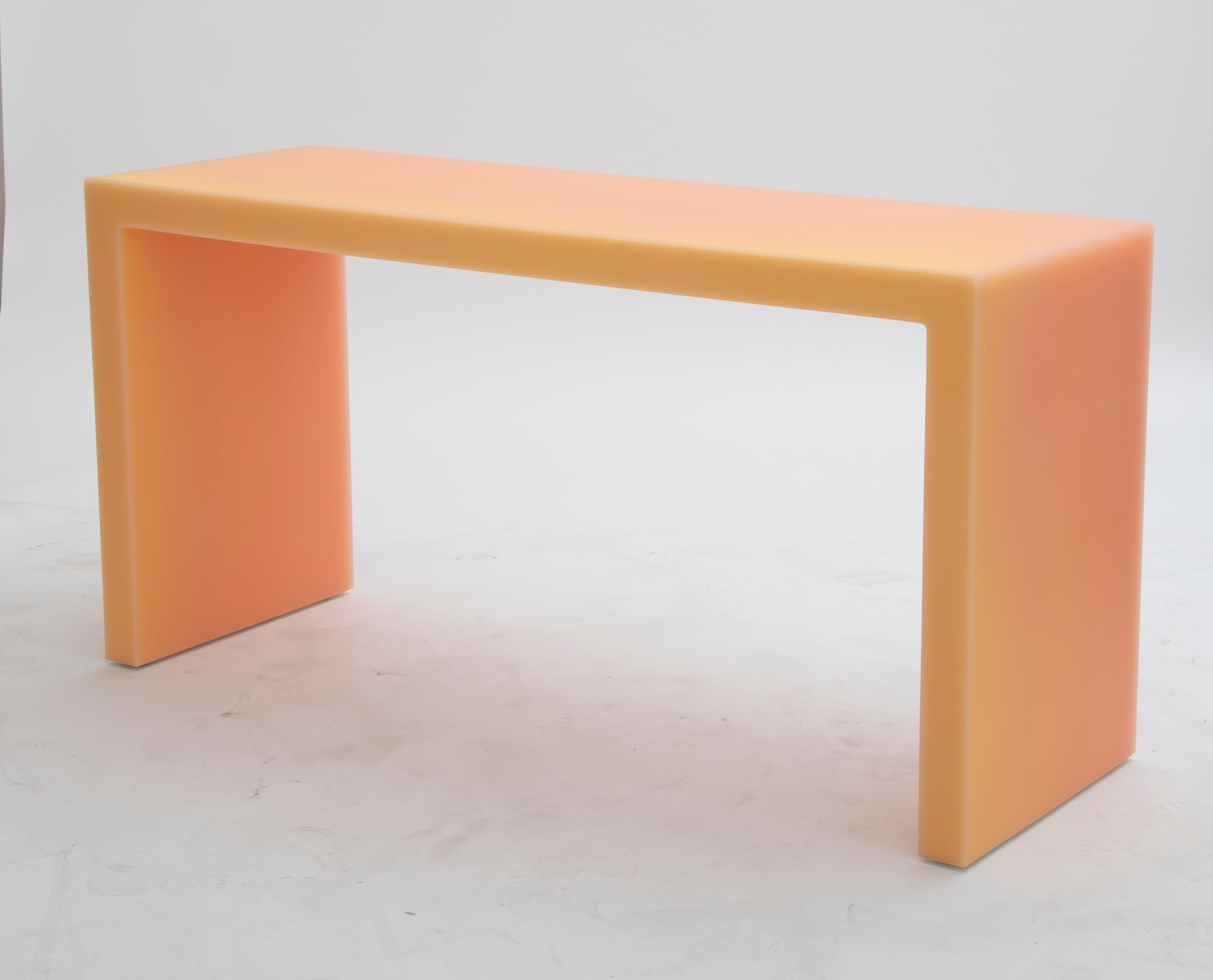 The resin desk features a matte exterior in a warm hue, attracting the eyes with shifting saturation in wavy patterns. This desk creates the illusion of perpetual motion in different directions depending on where the observer is.