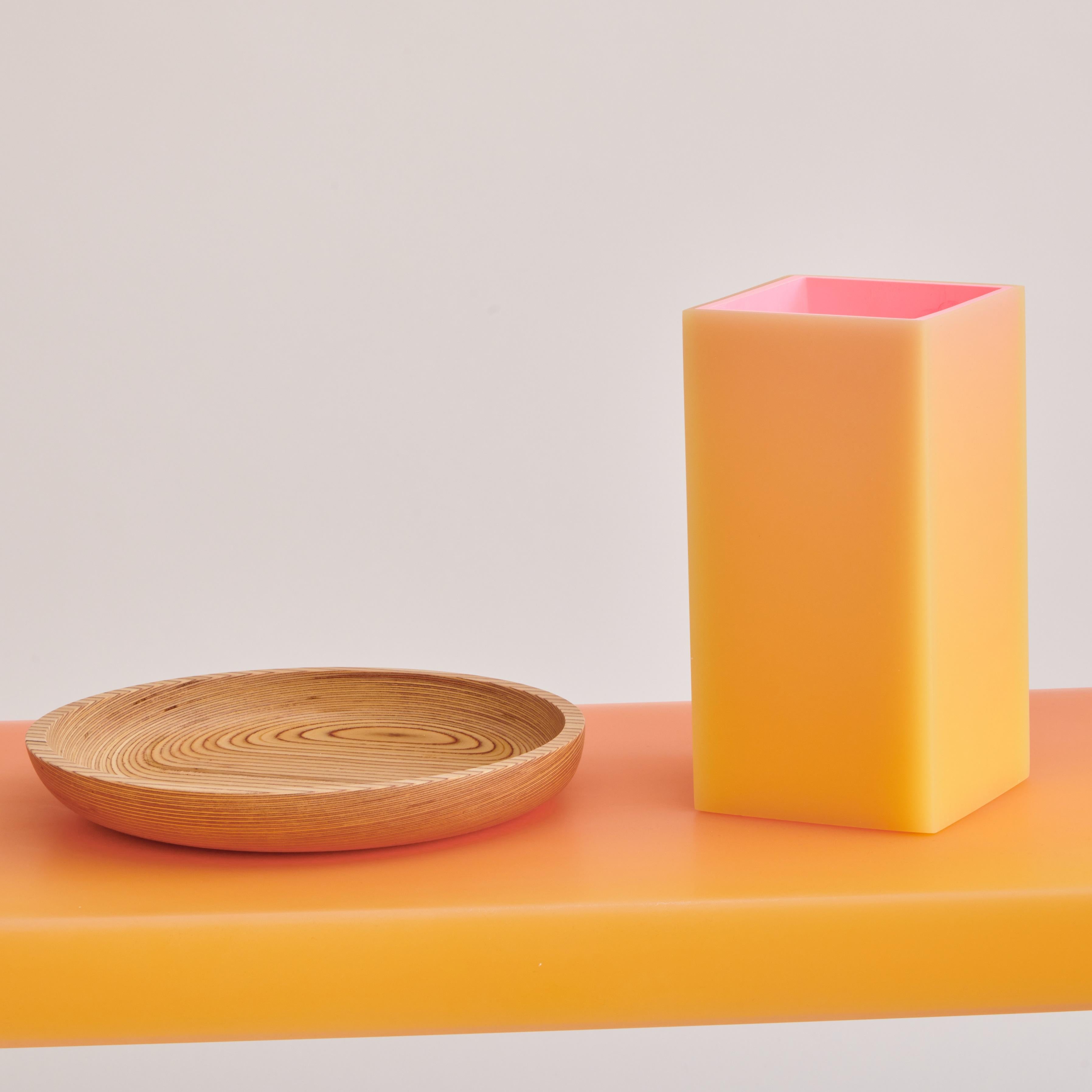 Quadratische Vase aus Harz in Orange und Gelb. Mit einem leuchtenden Äußeren, dessen Farben sich im pfirsichfarbenen Farbspektrum mischen, und einem rosafarbenen Inneren darunter.