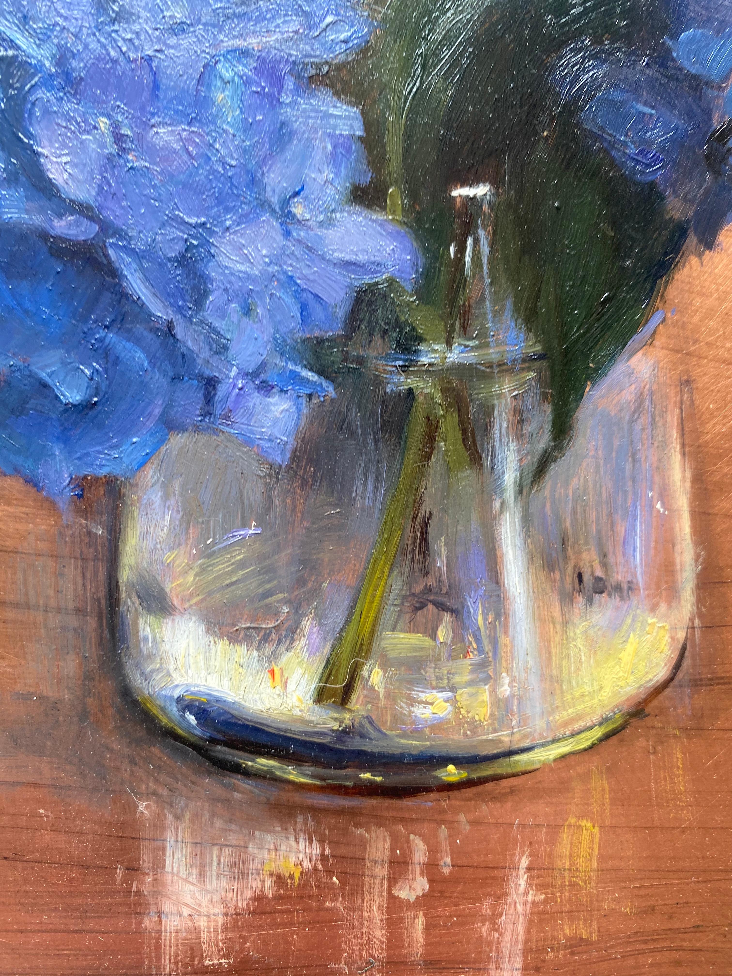 Painted with oil on a small 8 inch by 6 inch slate of copper, a small arrangement of blue hydrangeas. The artist, Melissa Franklin Sanchez, allows the bare copper to speak for itself in the negative space. The glass vile that holds water and the