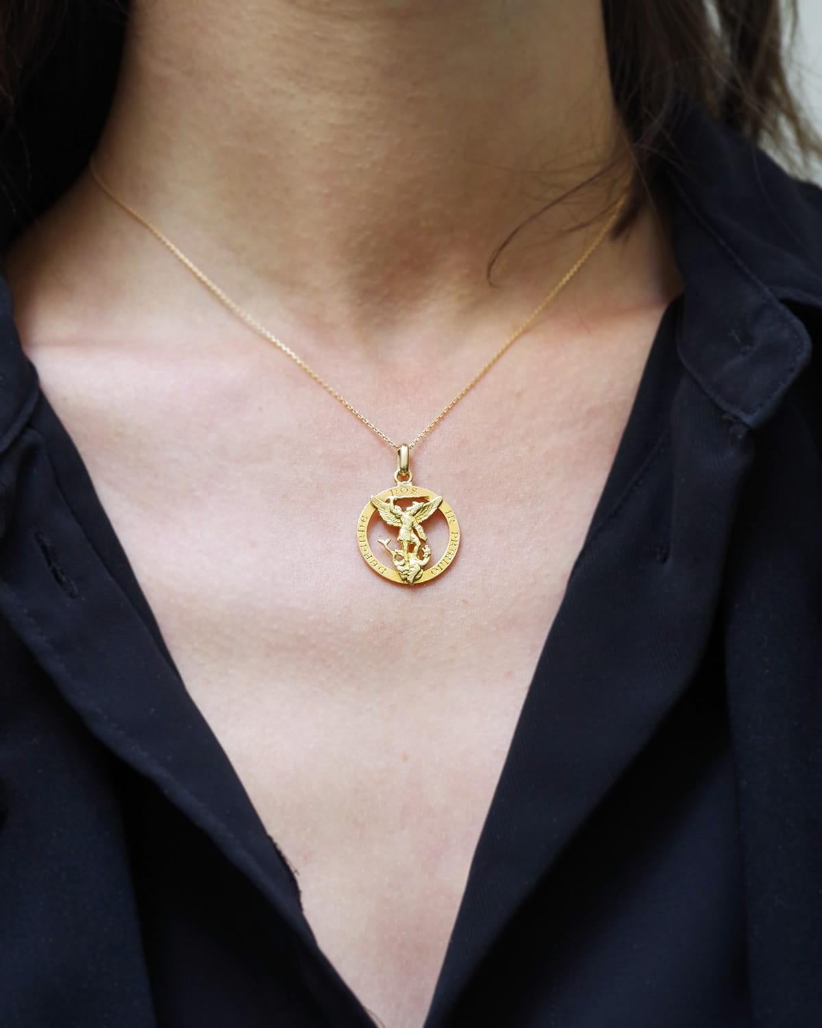 Colgante Mellerio Arcángel San Miguel de oro de 18 quilates. La medalla representa al Arcángel San Miguel matando al dragón, rodeado de la inscripción latina 