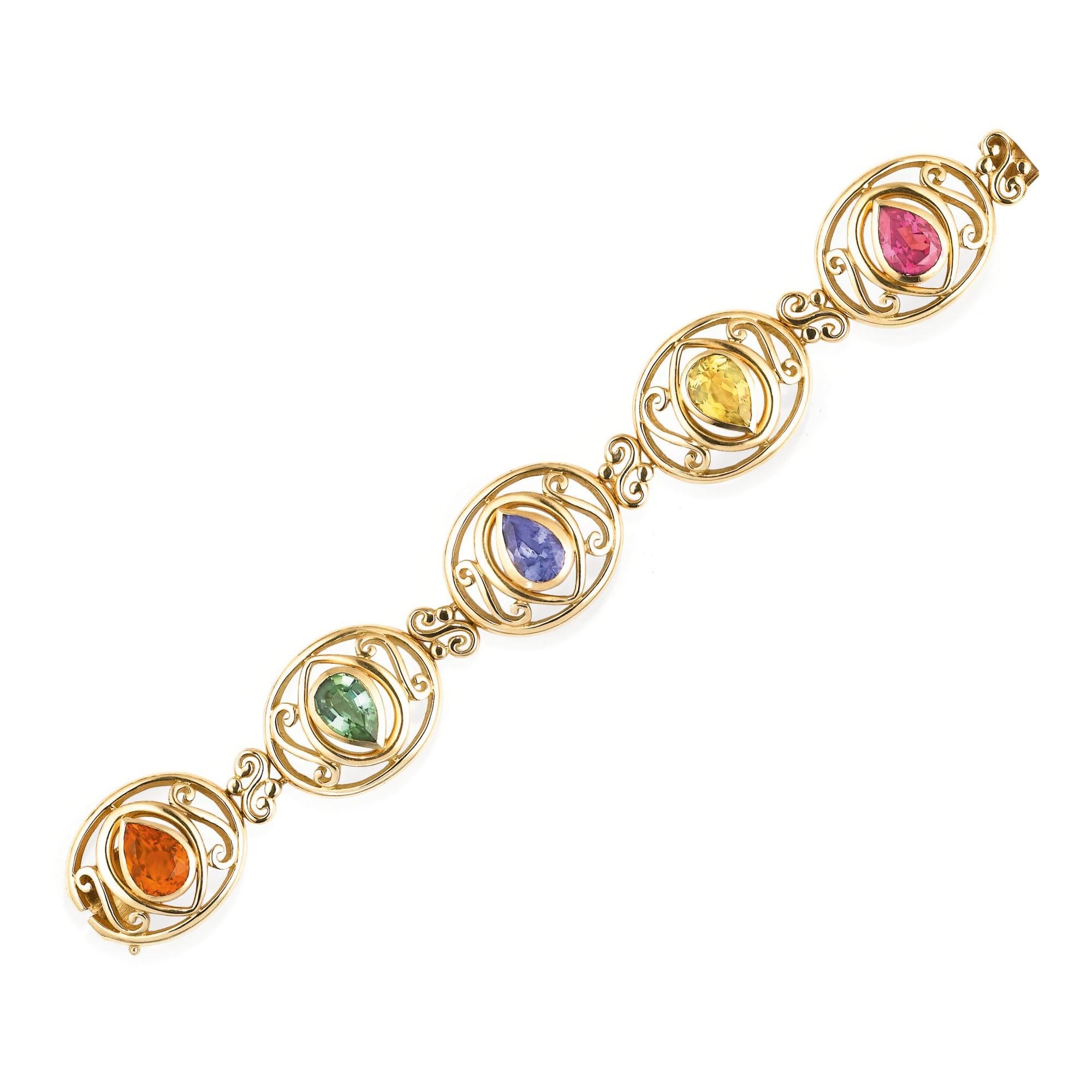 A stylish link bracelet by Mellerio composed of five oval openwork links collet-set with a pear-shaped citrine, a green tourmaline, a tanzanite, a yellow beryl and a rhodolite. 18 karat gold, made in France. Length approximately 170mm.