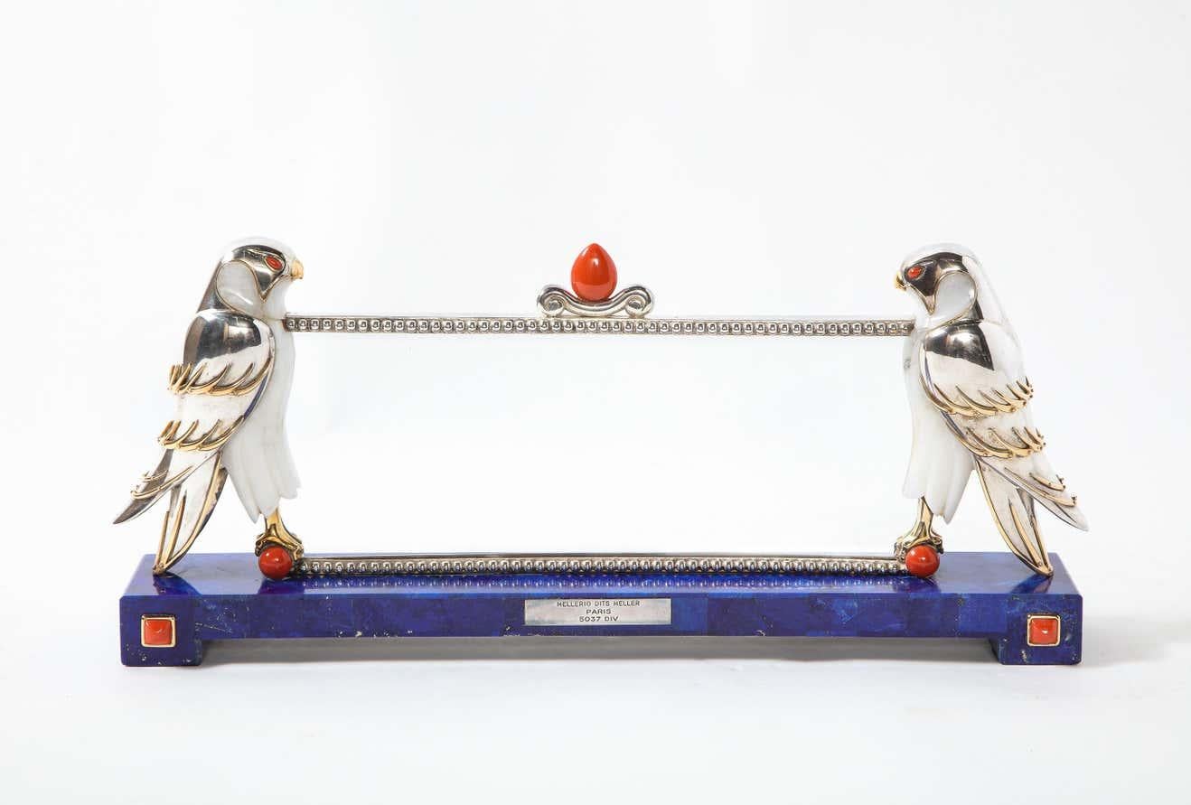 Mellerio Paris, A Large Silver, Gold, Lapis Lazuli, Coral, and Hardstone Picture Photo Frame with Two Falcons.  

France, circa 2000  

The frame resting on a lapis lazuli base with square coral cabochons and a plaque engraved MELLERIO DITS MELLER /