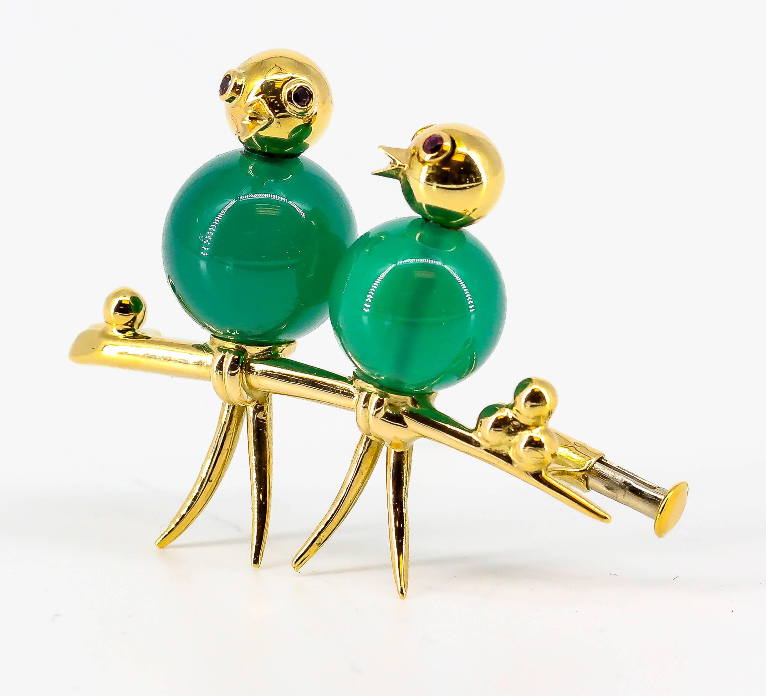 Whimsical chalcedony, ruby and 18K yellow gold brooch by Mellerio. It resembles two birds perched next to each other, with green chalcedony bodies, rich red rubies as eyes and 18K yellow gold setting.

Hallmarks: Mellerio Paris, reference numbers,