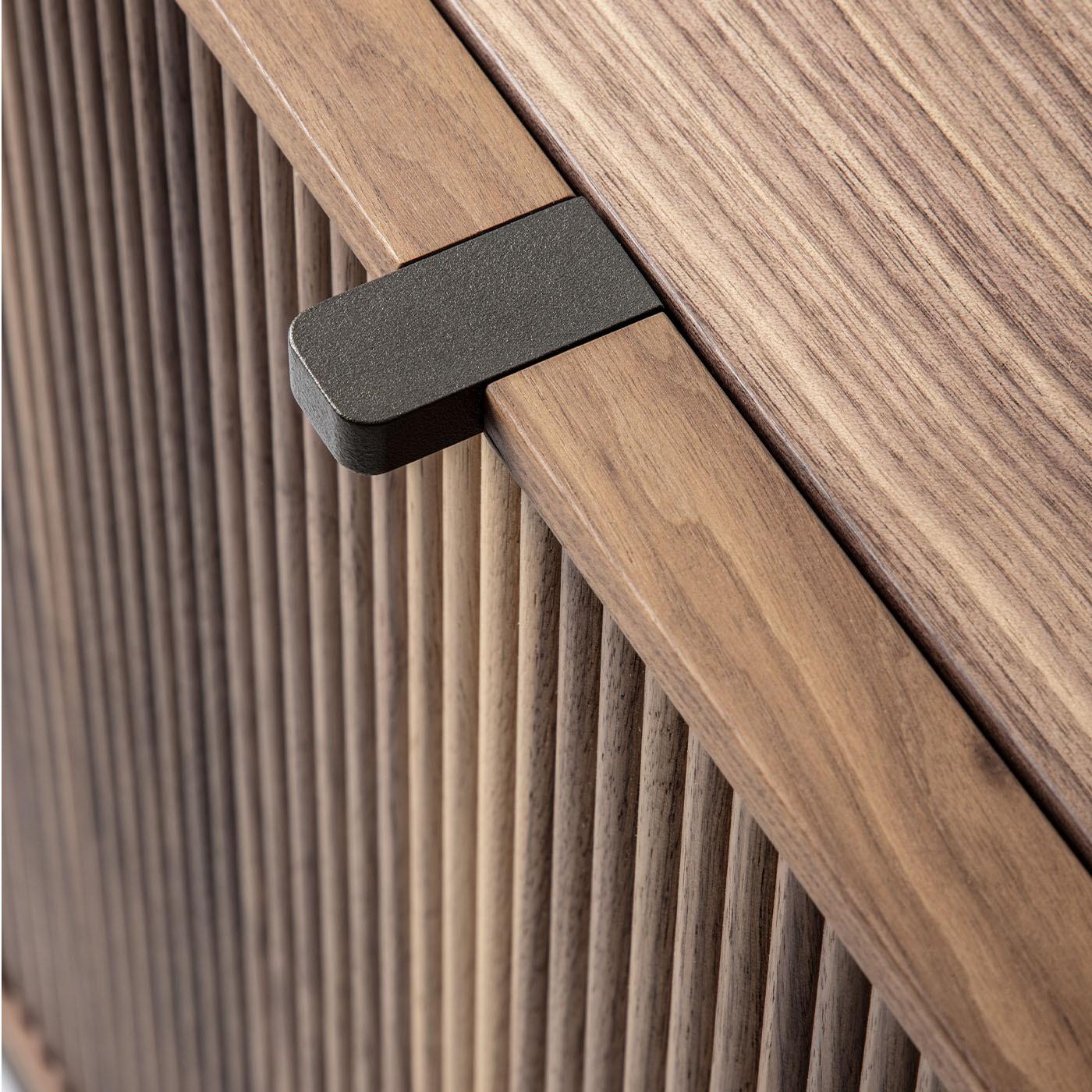 Distinguished by its Canaletto walnut wood and contemporary metal base, this storage masterpiece features a wooden top, two elegantly fluted wood doors, and three drawers adorned with plush leather fronts. Each detail is meticulously crafted to
