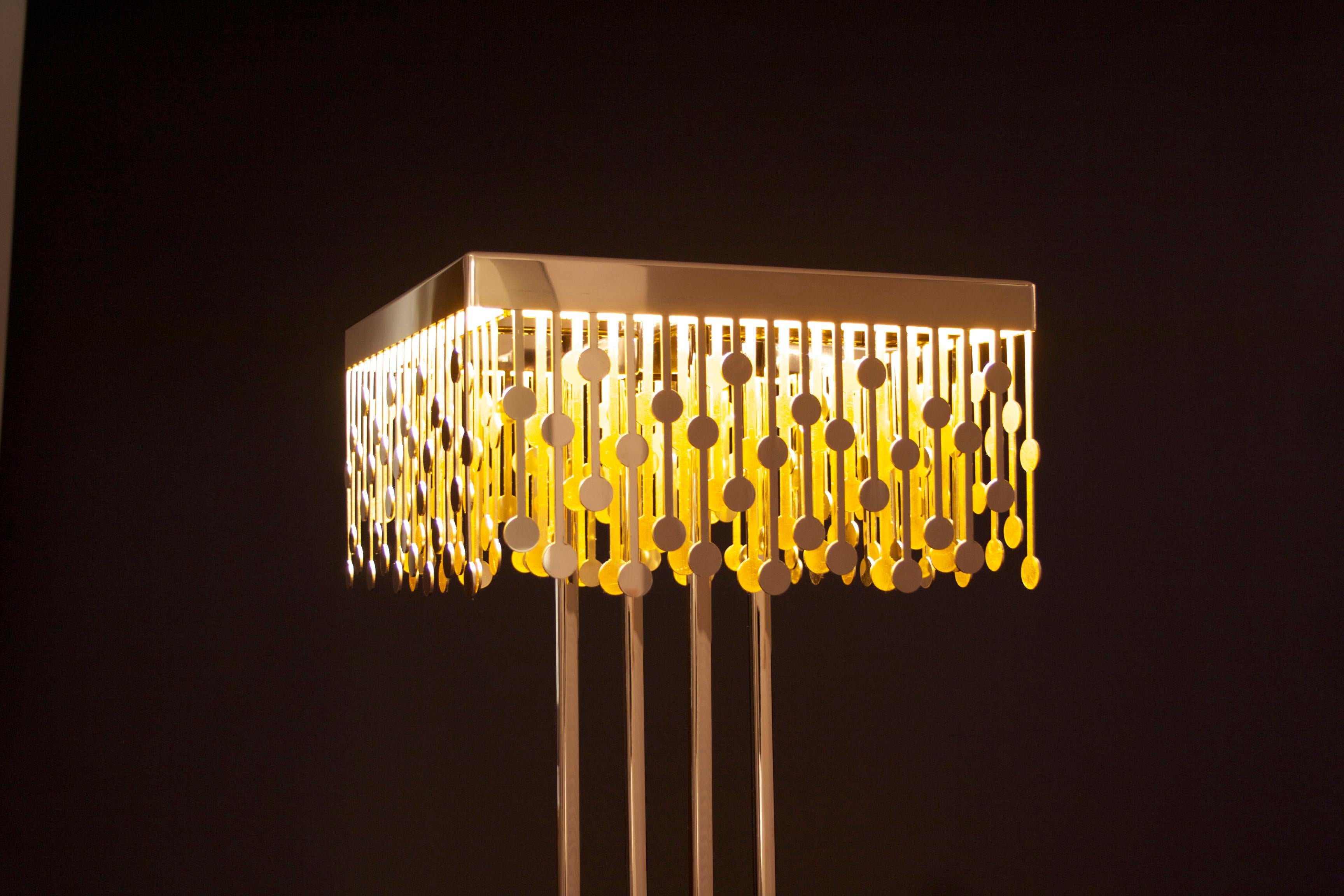 La lampada a sospensione Melody è uno splendido pezzo d'illuminazione d'ispirazione Art Déco realizzato in acciaio inossidabile lucido, che emana un fascino lussuoso e senza tempo. L'interno della lampada è rivestito in foglia d'oro, che quando si