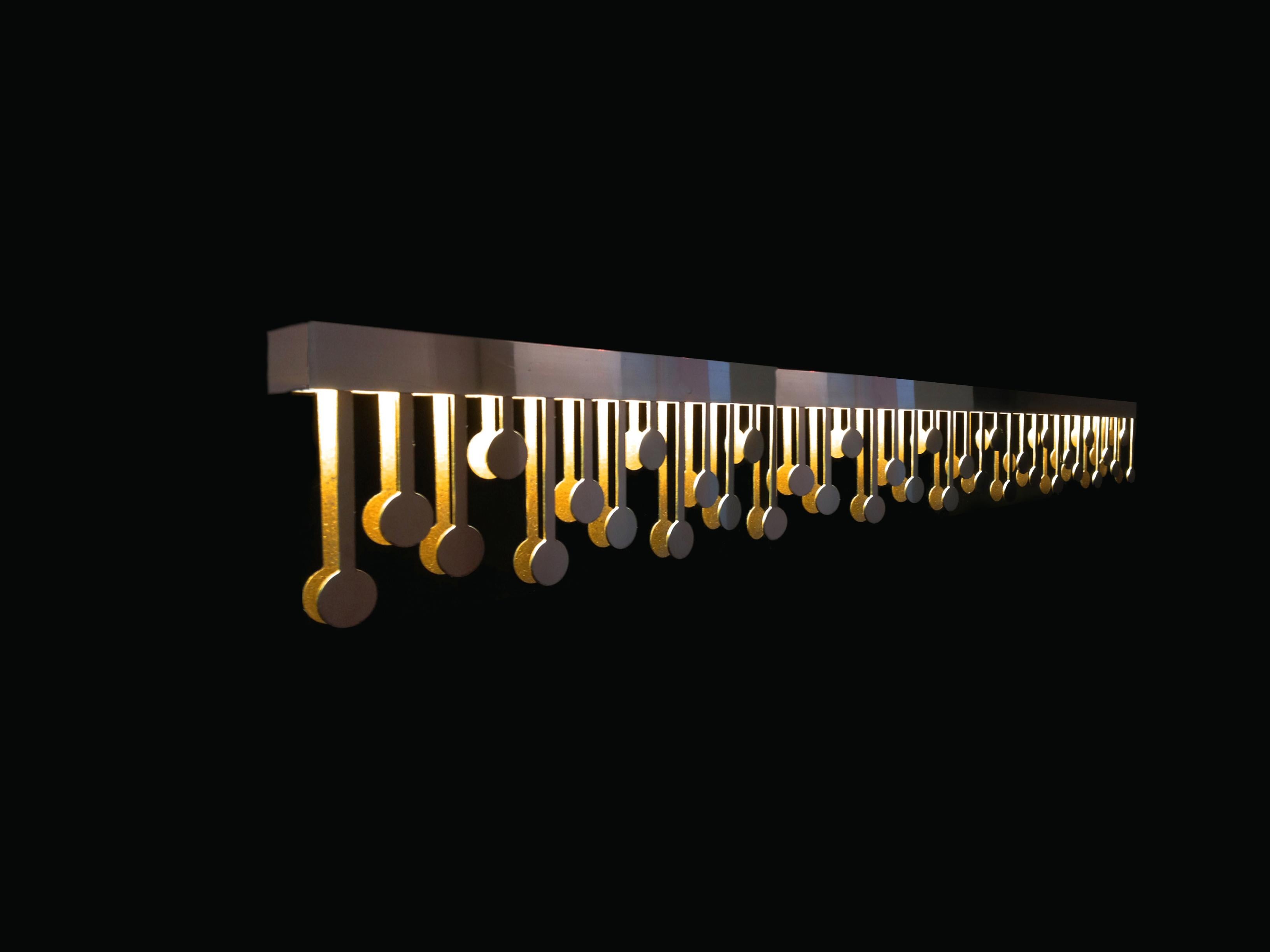 La lampada a sospensione Melody, di forma allungata, è uno splendido pezzo di illuminazione di ispirazione Art Déco realizzato in acciaio inossidabile lucido, che emana un fascino lussuoso e senza tempo. L'interno della lampada è rivestito in foglia