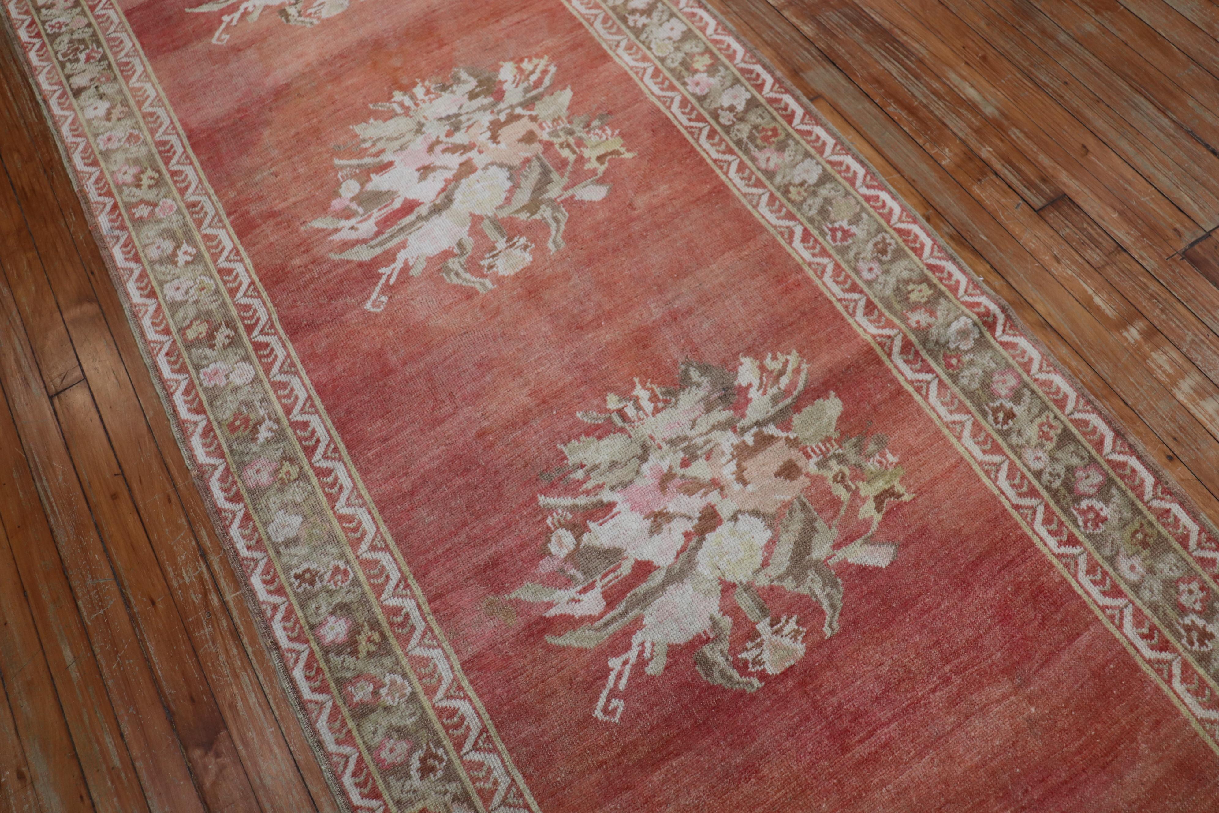 Early 20th century melon red field Turkish Ghiordes runner with an enchanting floral motif 

Measures: 3'5” x 12'9”.