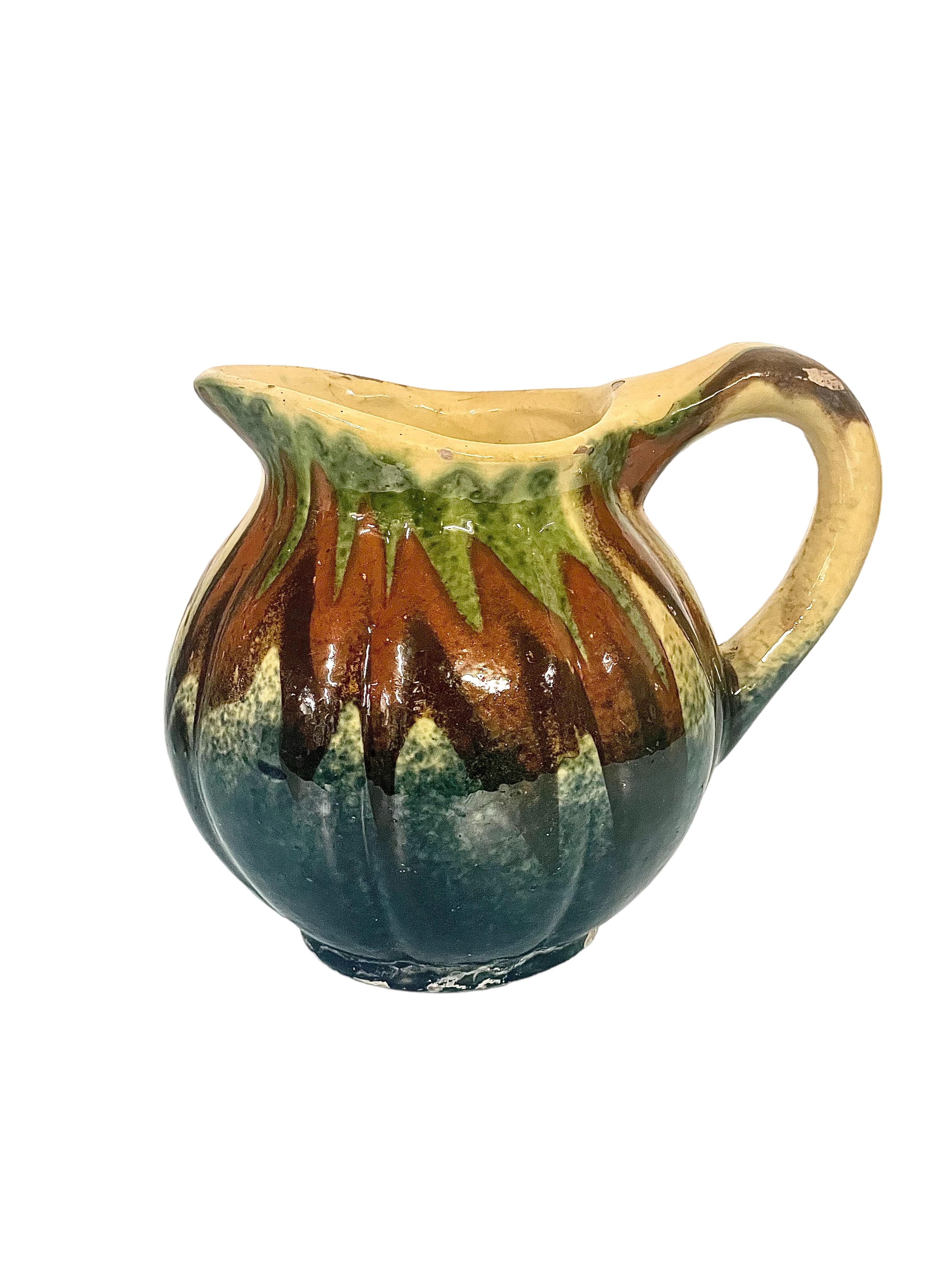 An interesting melon-shaped drip-glazed milk or water jug, decorated in shades of cream, brown and green. This tiny 19th century jug has a good sized handle and wide spout, and would be ideal for a country-style home or farmhouse kitchen. 19th