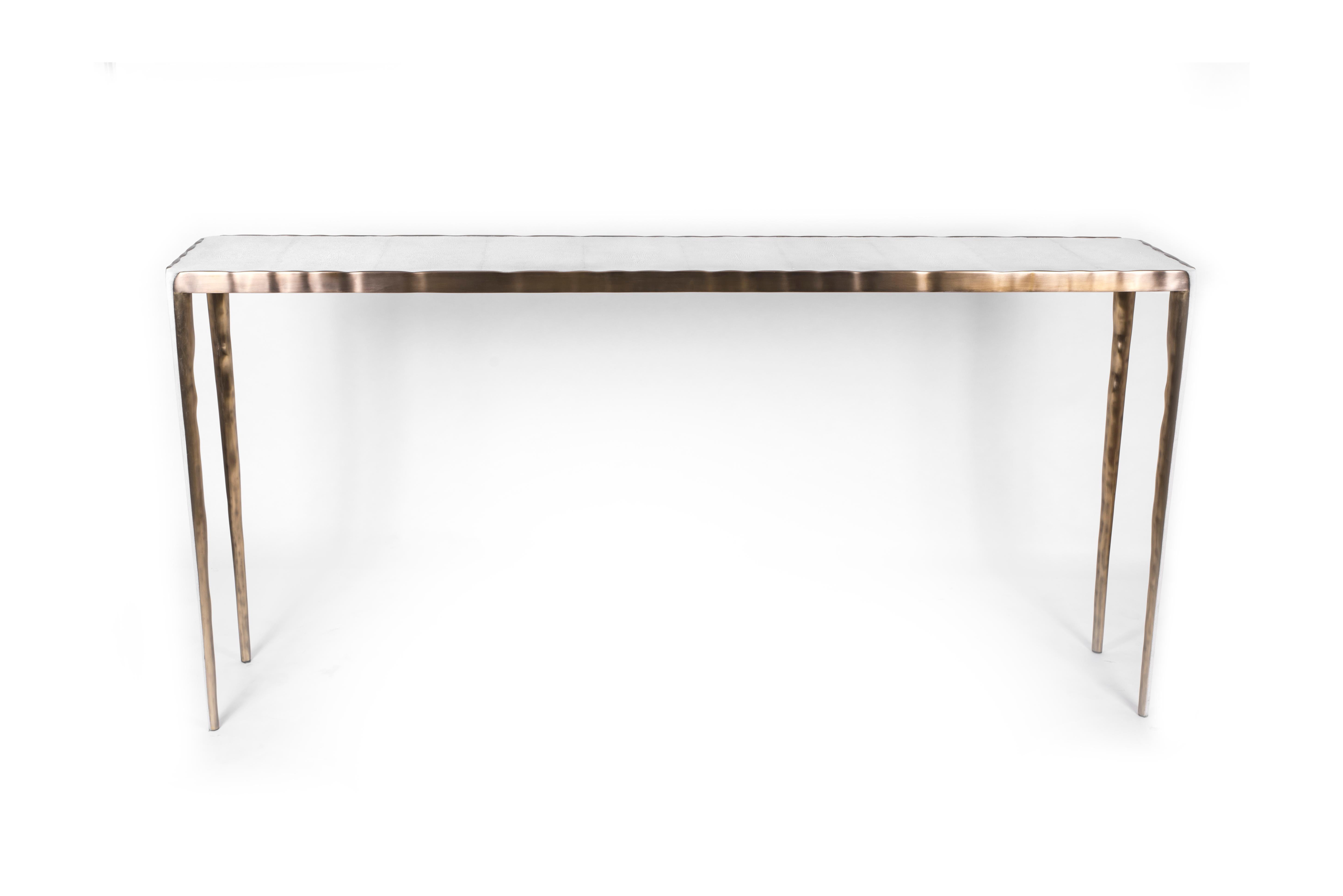 Le design simple mais élégant de la table console melting en fait un meuble neutre adaptable. Le plateau en galuchat crème est encadré d'une surface irrégulière en laiton bronze-patine qui crée un effet de 