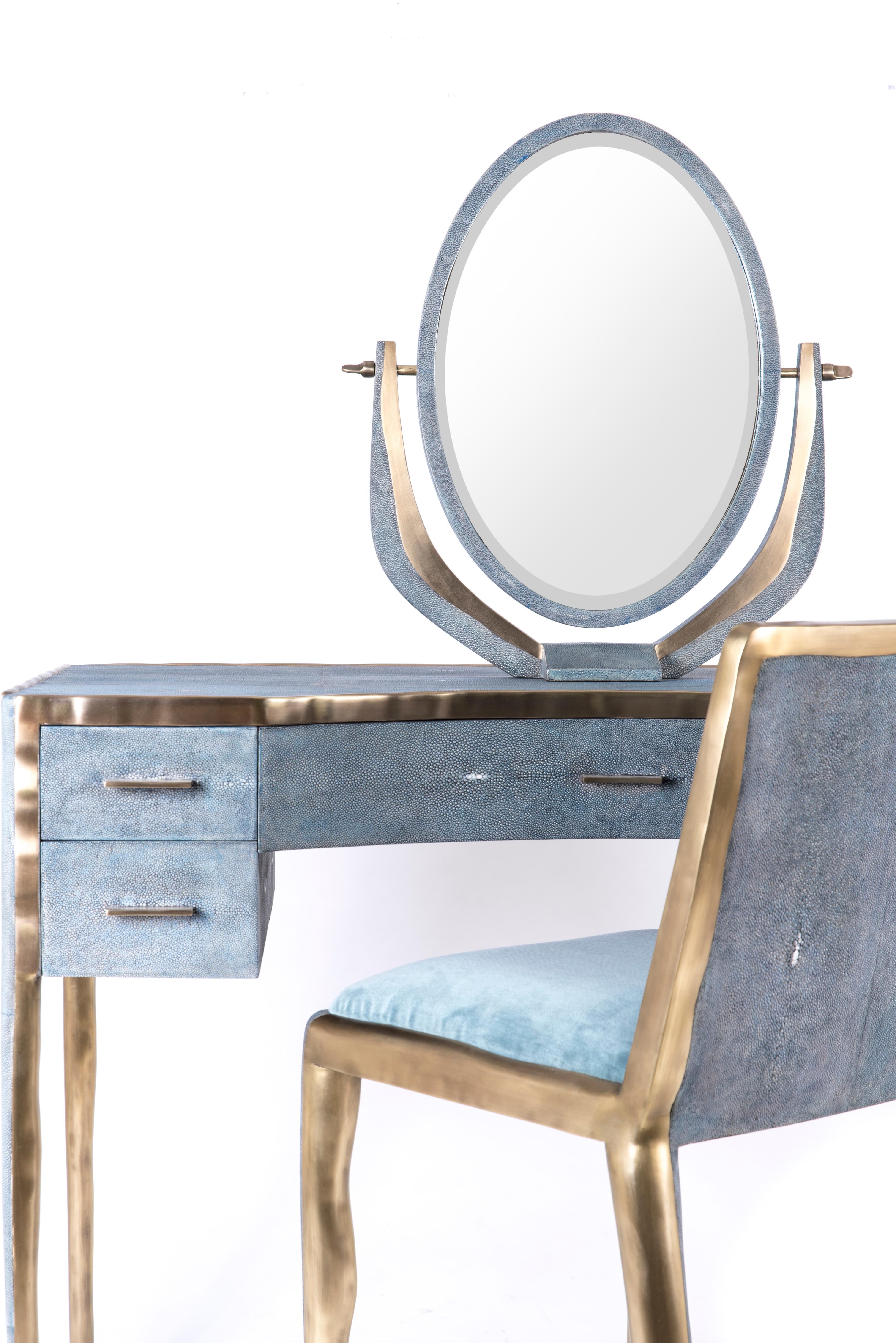 The melting vanity table's simple but elegant design, makes for an adaptable elegant piece of furniture. The blue shagreen inlaid surface is framed with an irregular surface bronze-patina brass that creates the 