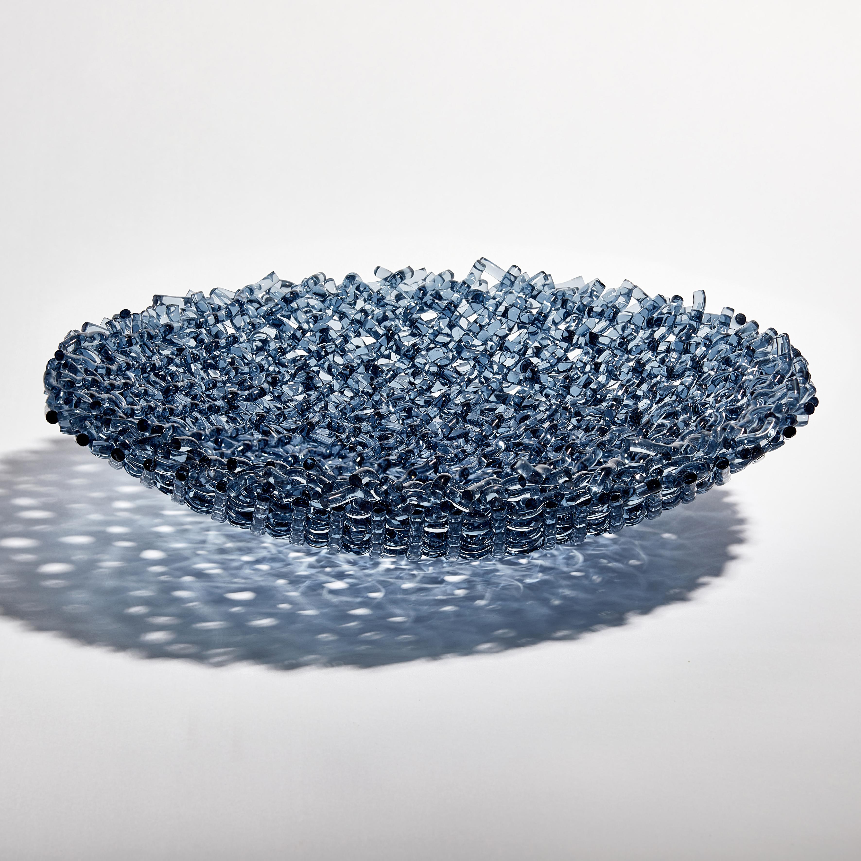 Meltwater is a unique clear glass sculptural centrepiece by the British artist Cathryn Shilling. Using chunky glass rods in steel blue, which are harder to source, Shilling weaves and layers these to beautiful effect. Being thicker than her usual