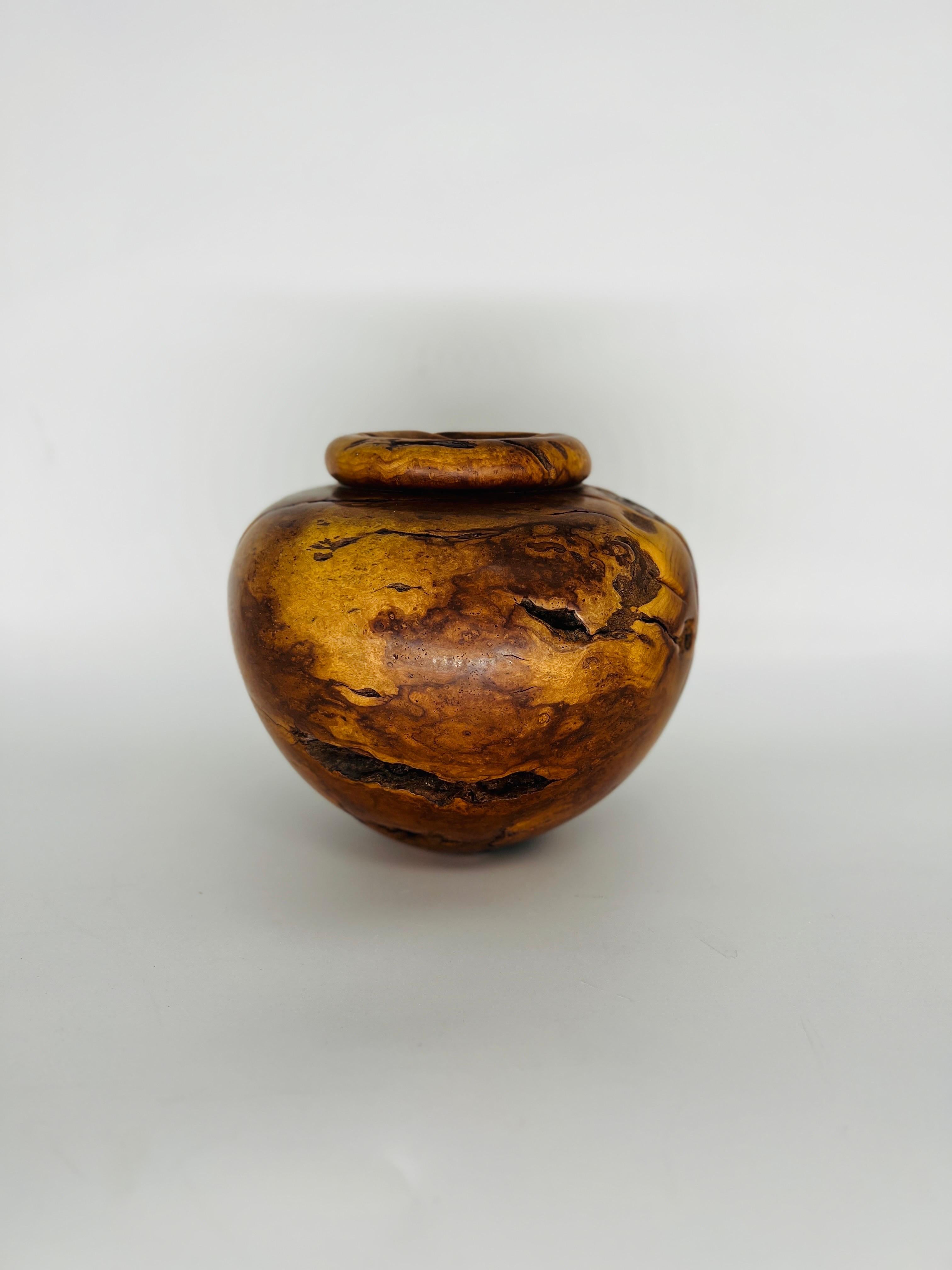 Melvin Lindquist (American, 1911-2000) Beautiful turned vase in Cherry burl with natural occlusions. Signed 2-82 Cherry Burl. 

Melvin Lindquist began turning in the 1930s as a vertical turret lathe operator for the General Electric Company. In