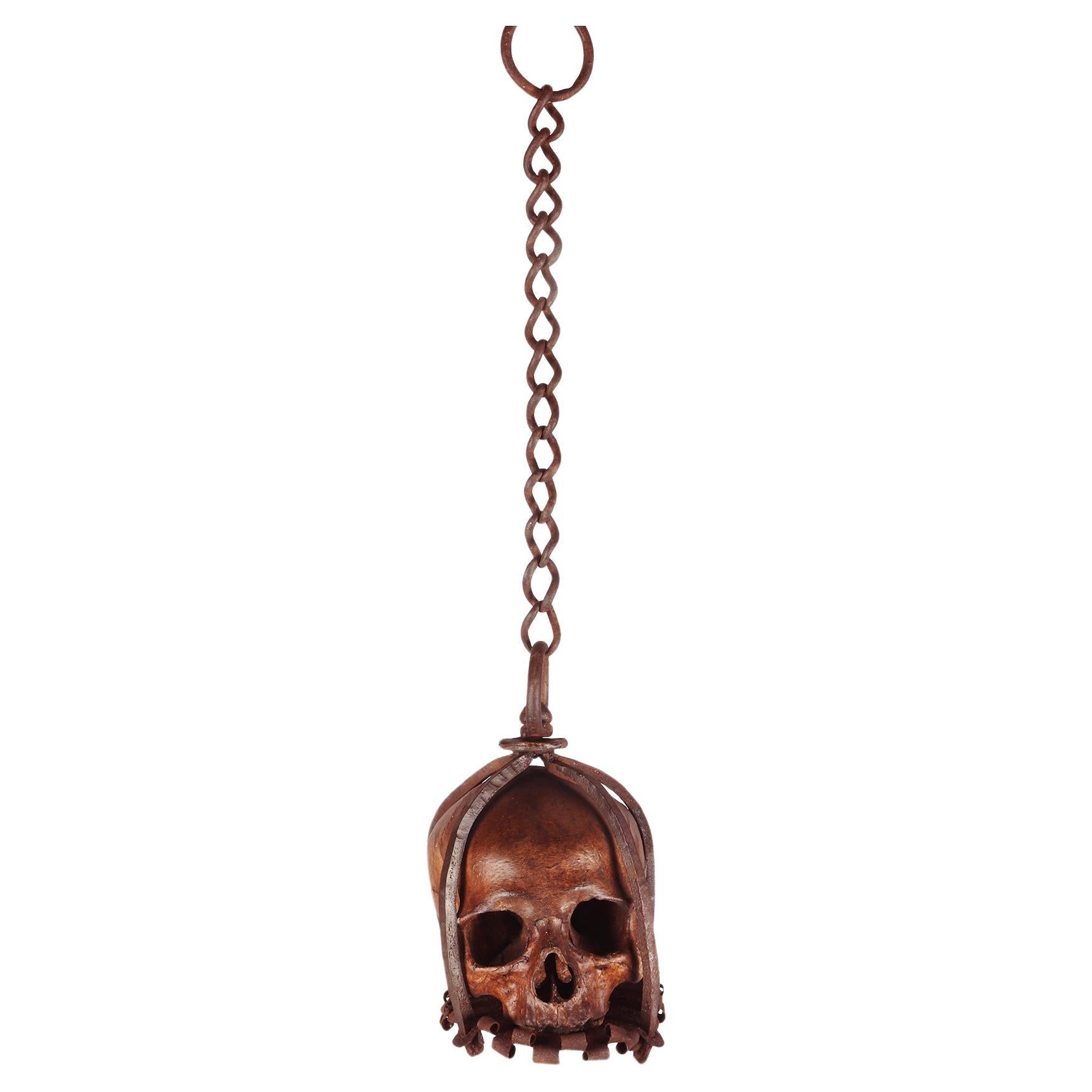 A rare example of Memento Mori from Wunderkammer depicting a skull caged in a forged iron structure, with a chain for hanging. The sculpture is made of scagliola plaster with a high artistic and executive level. It rests on a coplanar base plate,