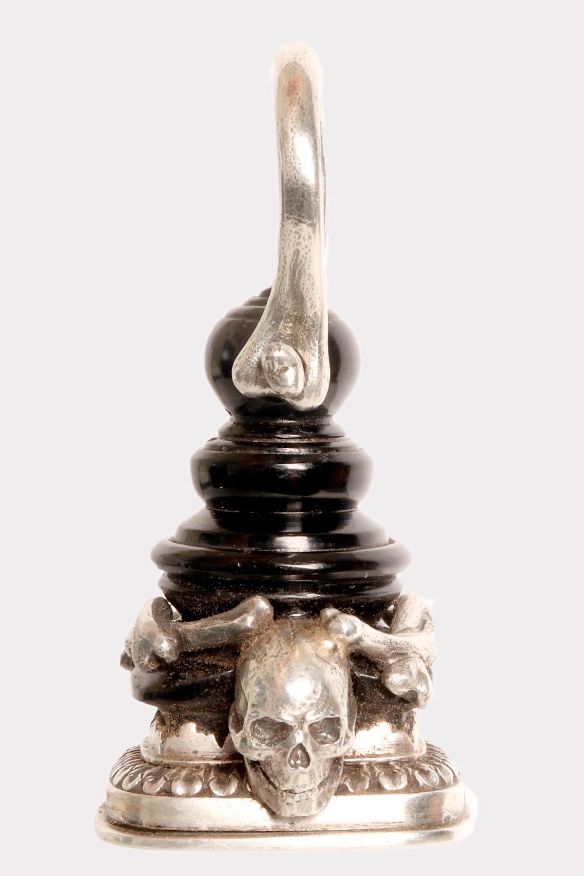 Chain seal in silver and jet.
The seal features a rectangular silver plate with a carved noble coat of arms representing a two-headed eagle. The matrix is crowned by a frame with a wavy profile enriched by sequential leaves. The body of the seal is