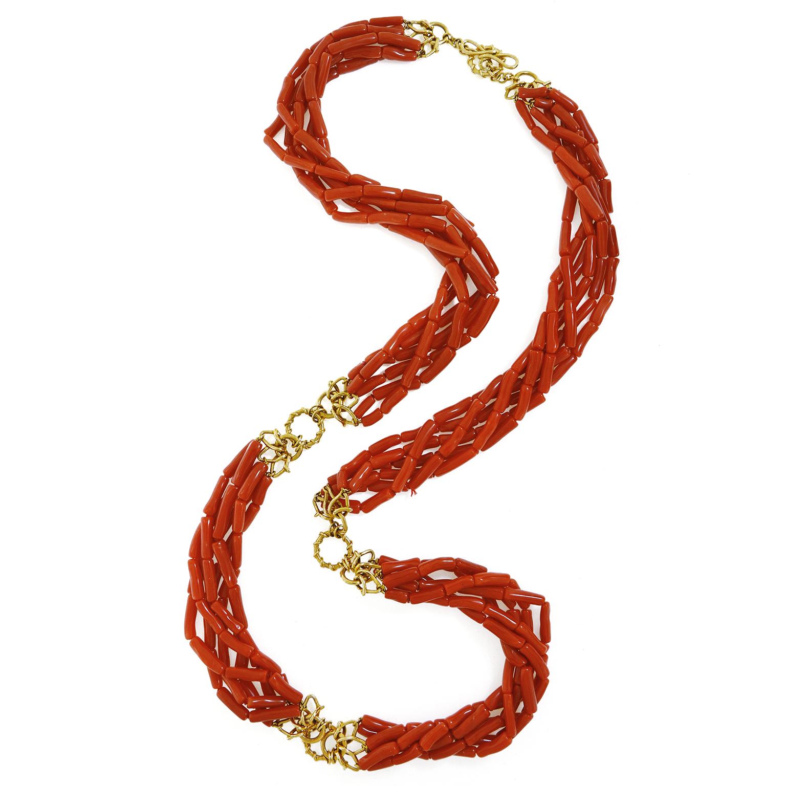 Diese Halskette besteht aus auffälligen roten Korallen, die in zylinderförmige Perlen geschnitzt sind. Die 6 Stränge sind zu einem Torso gedreht, was einen einzigartigen Look ergibt. Drei Vs aus 18 Karat Gelbgold befinden sich an beiden Enden der