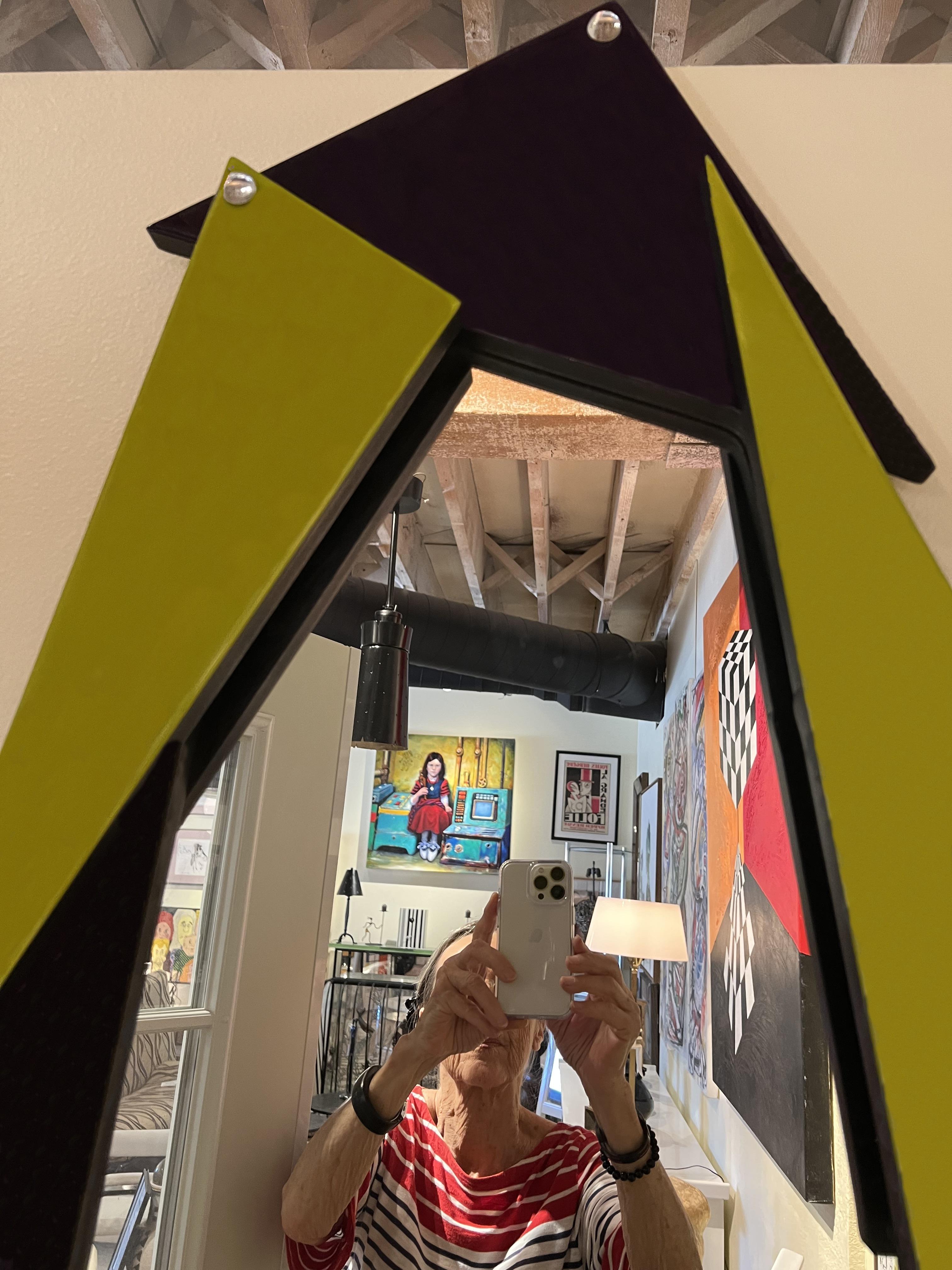 This piece features a mirror framed with dark purple and olive green glass triangles.
Memphis Design is a new style that only starts in 1980. The 80s was a period of eclectic transformation, where previous trends were rejected but borrowed from, and