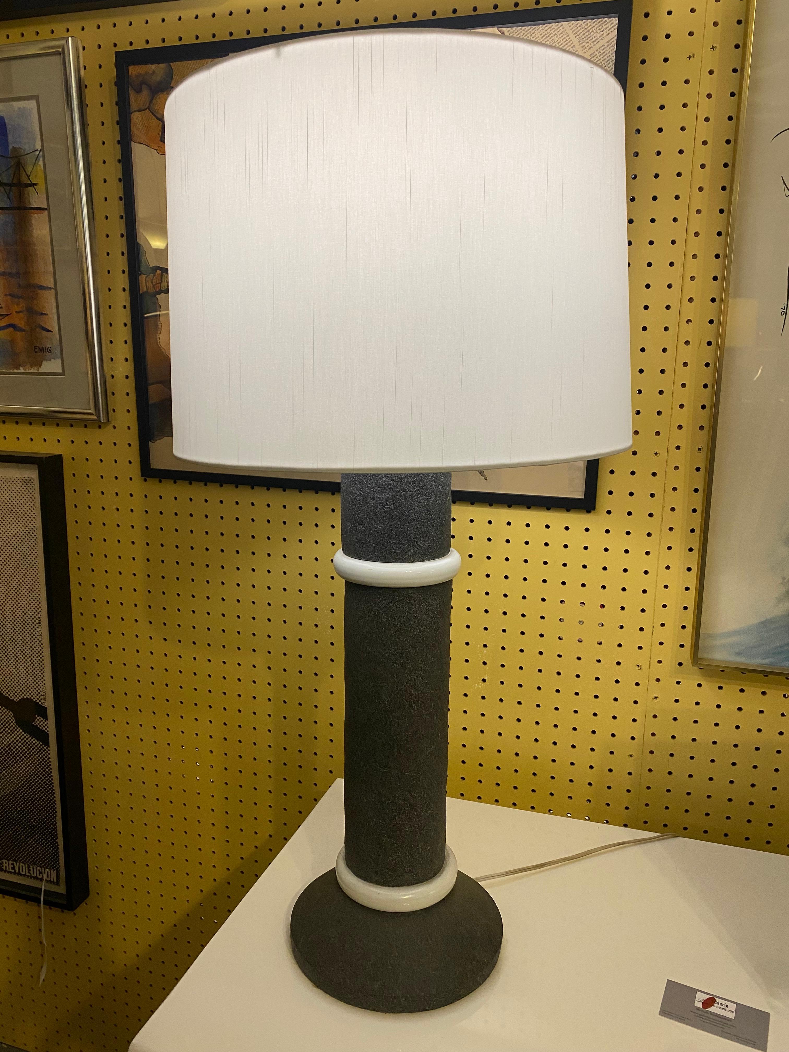 Esta escultural lámpara de sobremesa presenta un diseño minimalista característico del estilo Memphis. Fabricado en resina gris y blanca, está definido por dos discos blancos decorativos superpuestos -uno situado en la base y el otro cerca de la