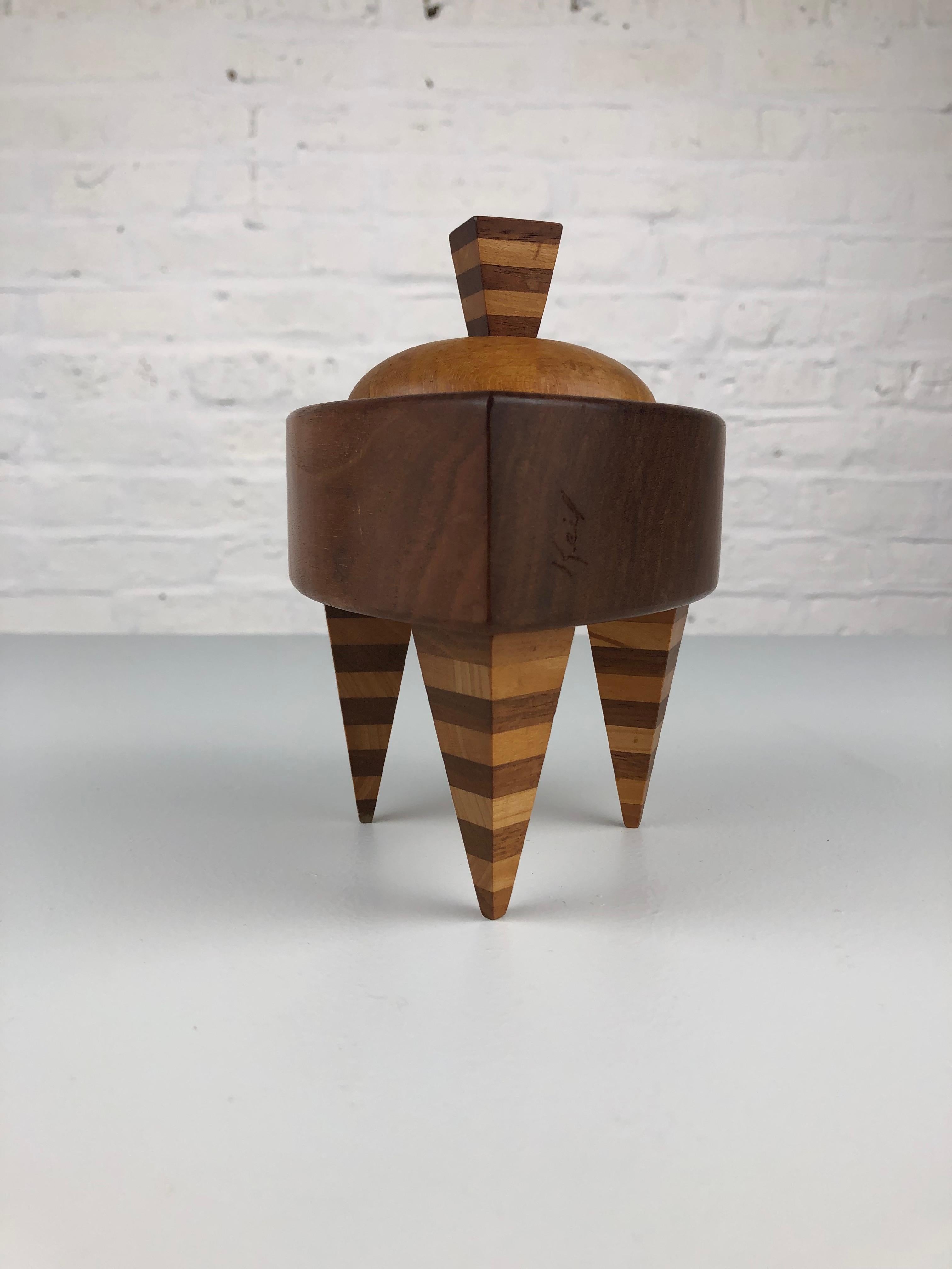 Exquisite handmade trinket box crafted from three distinct woods by a talented American Woodworker in the vibrant 1990s. This piece showcases a masterful play of high contrast stripes and bold, frank perspectives, reminiscent of the iconic work of
