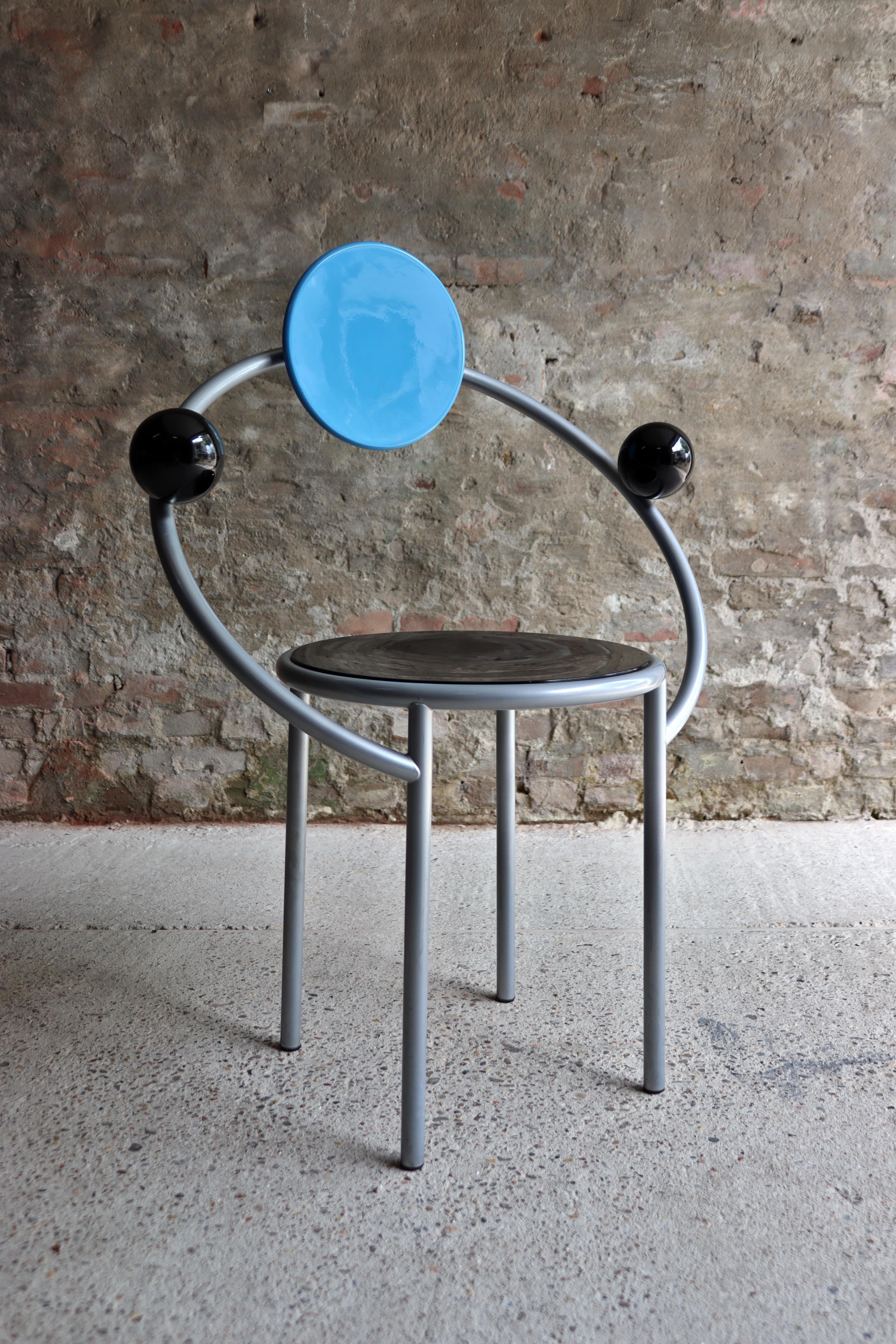 Striking and bold, this chair designed by Michele De Lucchi in 1983 for Memphis will be a superb addition to a contemporary dining room, study, or entryway when used as a unique accent piece. The sophisticated design evokes planetary orbits in a