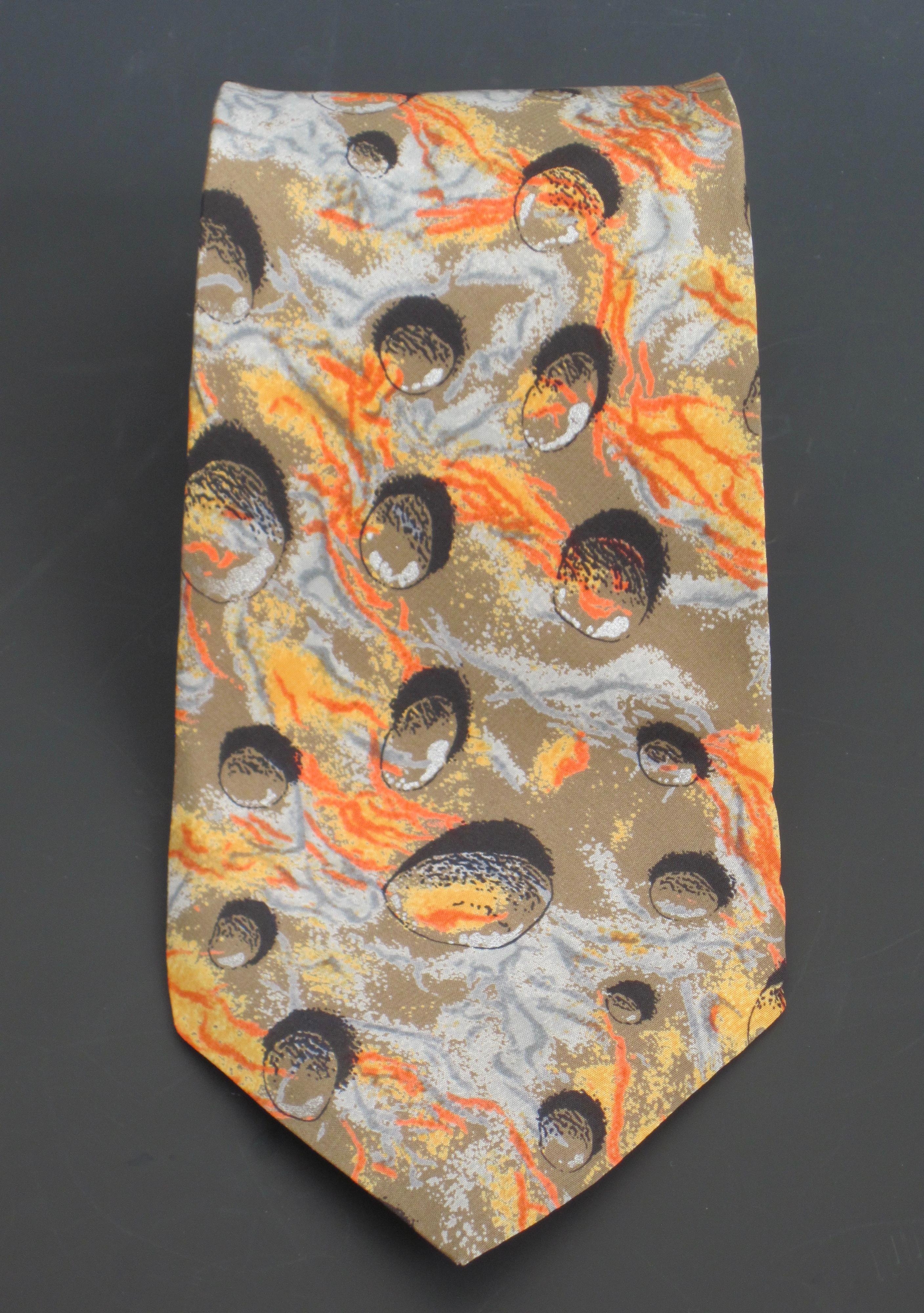 Italian silk necktie by Andrea Branzi, circa 1984. An original Memphis Milano design with shades of orange and gray on a khaki background with 3 dimensional black round shapes resembling rocks. This distinctive tie design reminds me of an