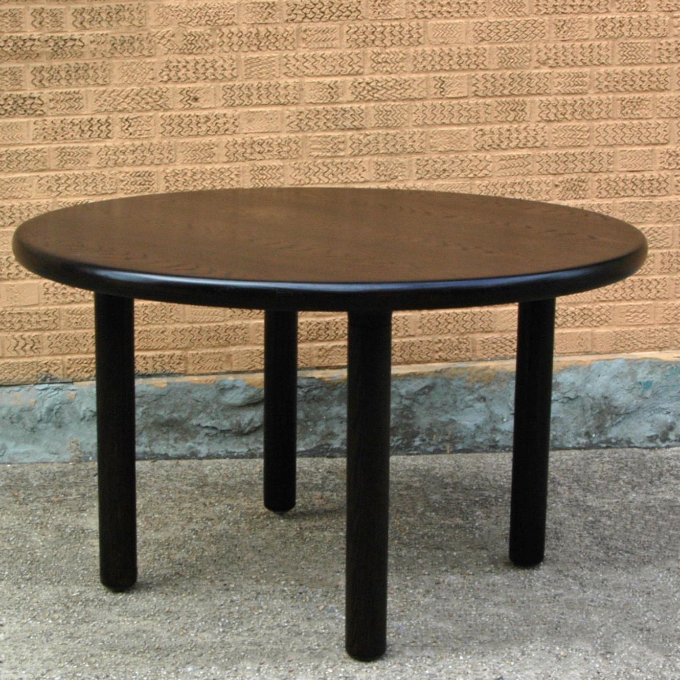 Memphis style, round dining table features rounded ebonized oak edges with four pillar legs.